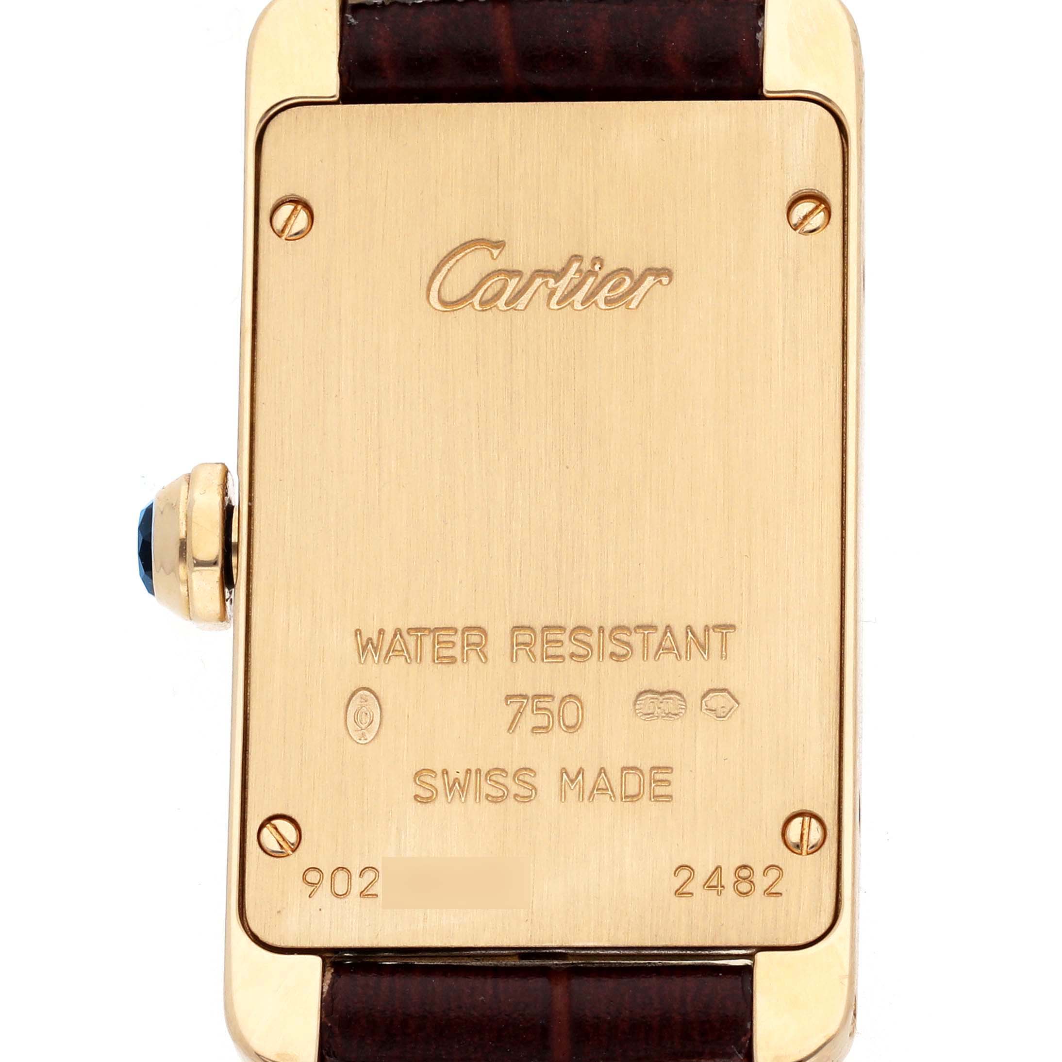The image shows the back case of the Cartier Tank Americaine W2601556 Women's Yellow Gold Beige Dial watch with engraved details and a visible crown on the left.