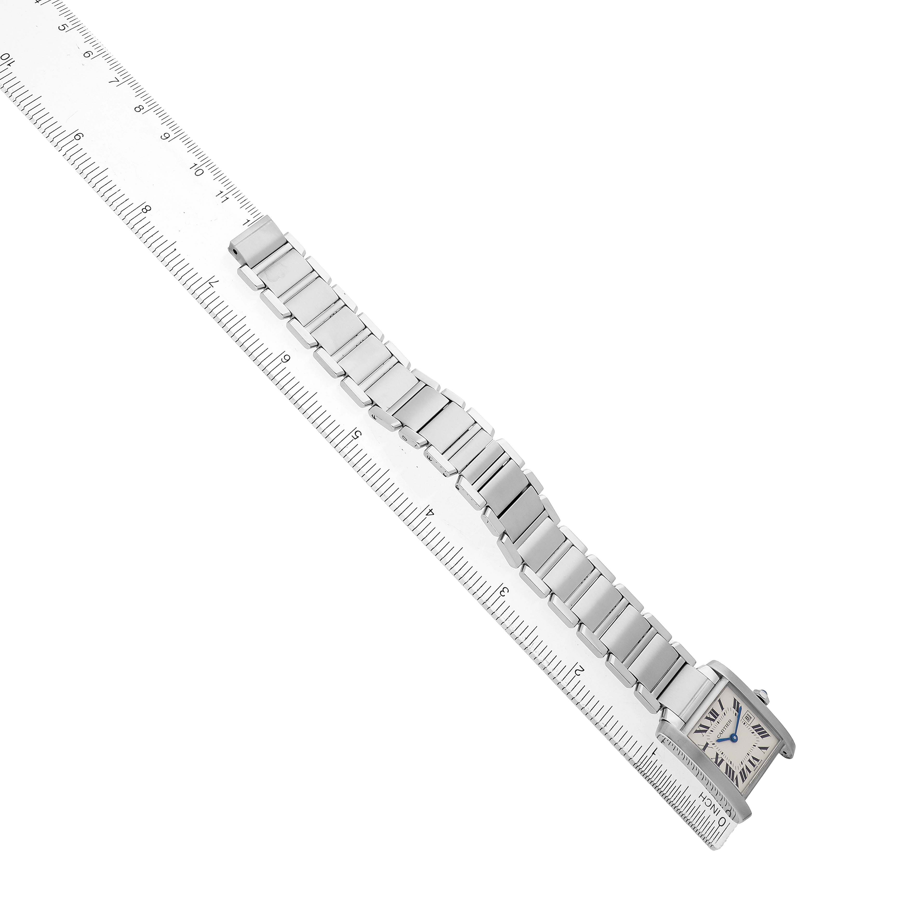 The Cartier Tank Française watch is shown from a top view, highlighting its rectangular case and metal bracelet alongside a ruler.