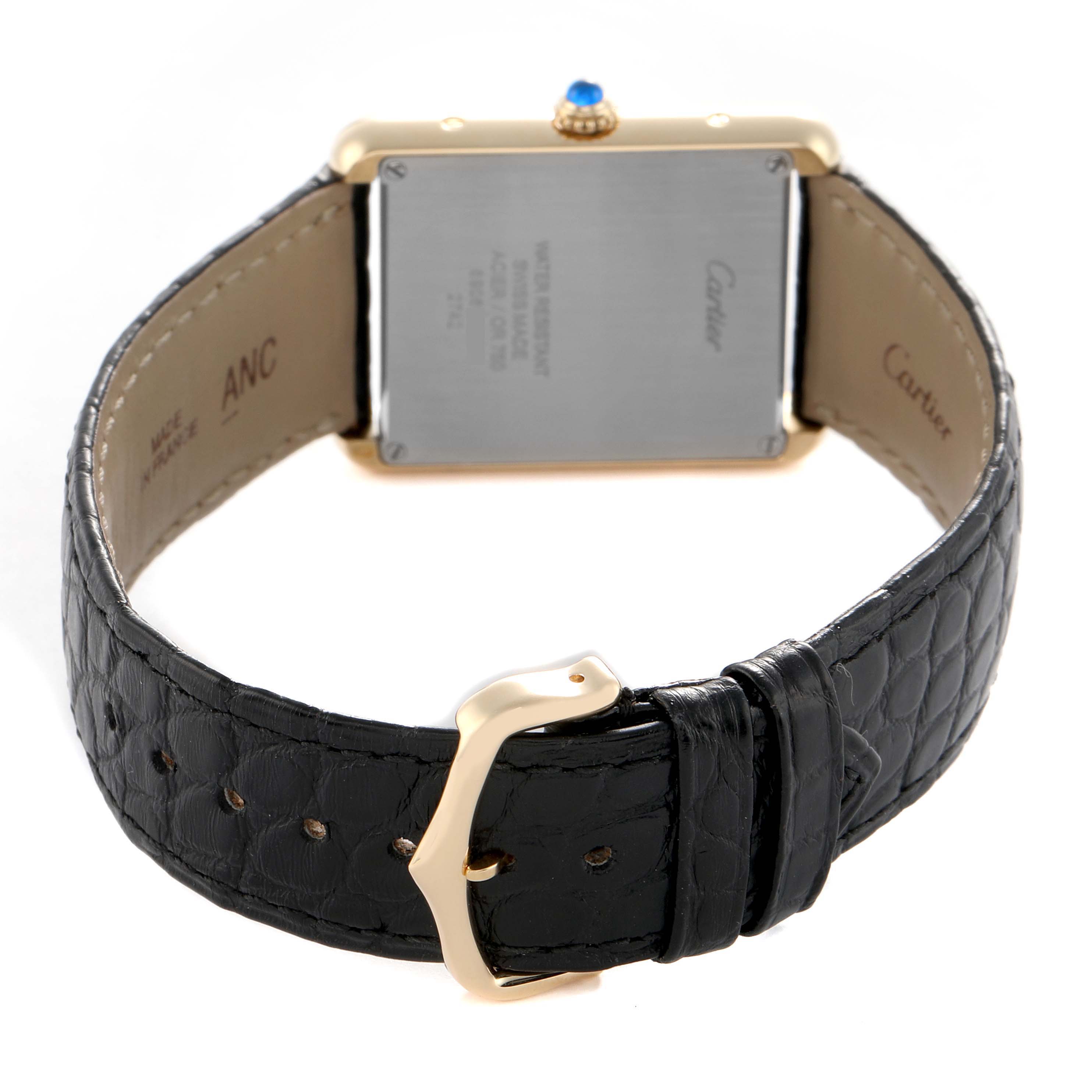 The Cartier Tank Solo W1018855 Men's Yellow Gold Silver Dial watch is shown from the back angle, highlighting the case back and black leather strap with a buckle.