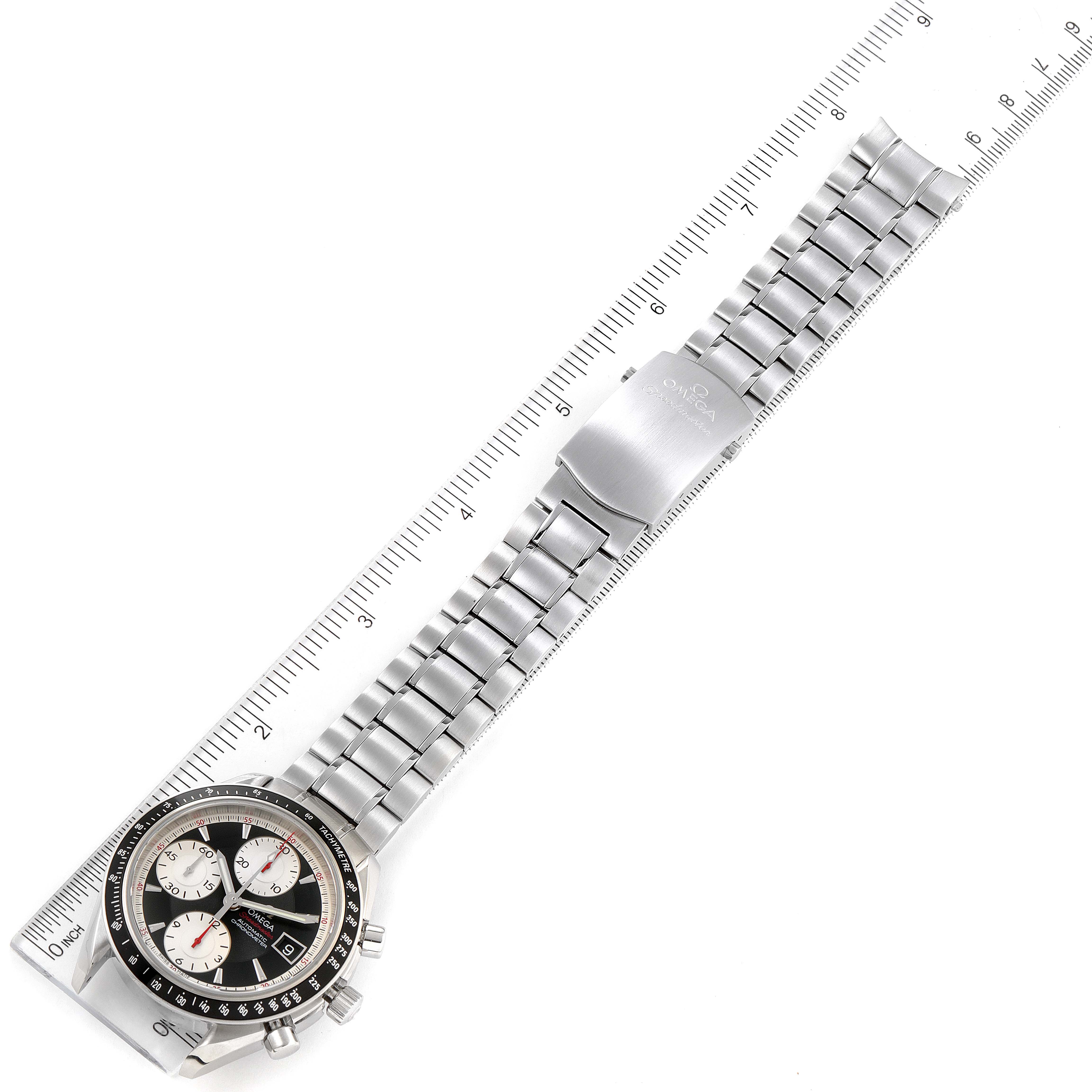 The image shows an Omega Speedmaster 3210.51.00 Men
s Stainless Steel Black Dial 3210.51.00 Men
s Stainless Steel Black Dial watch laid flat, emphasizing its bracelet and clasp, alongside a ruler for size reference.