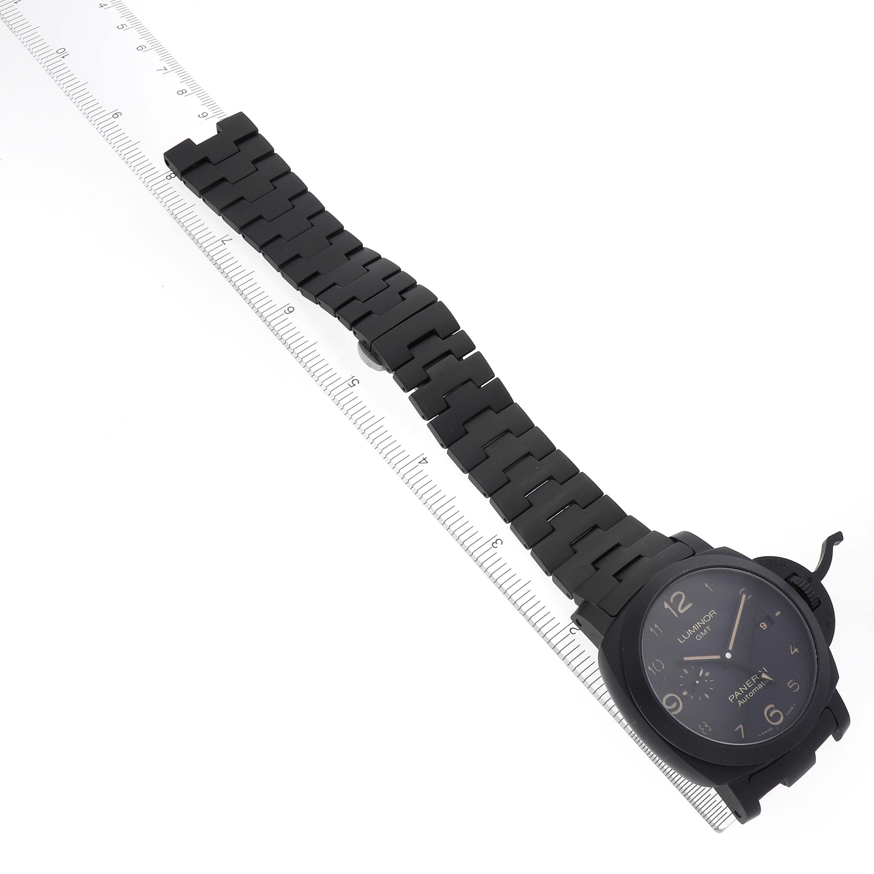 The Panerai Luminor PAM01438 Men
s Ceramic Black Dial PAM01438 Men
s Ceramic Black Dial watch is shown at an angle, displaying the face, bracelet, and clasp alongside a measuring ruler.