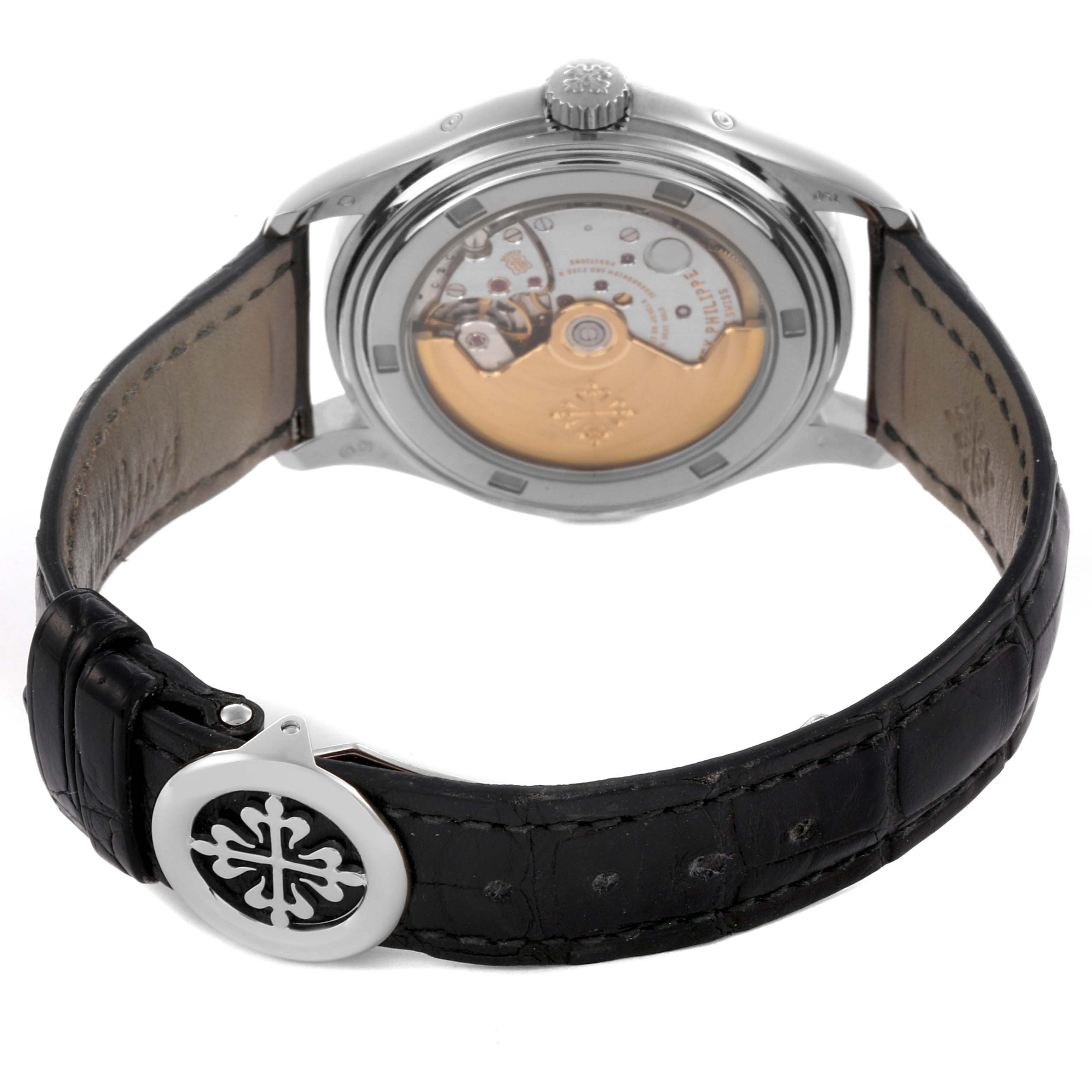 The Patek Philippe Calatrava 5146G Men's White Gold White Dial 5146G Men's White Gold White Dial watch is shown from the back, highlighting its movement and leather strap with a logo-decorated clasp.