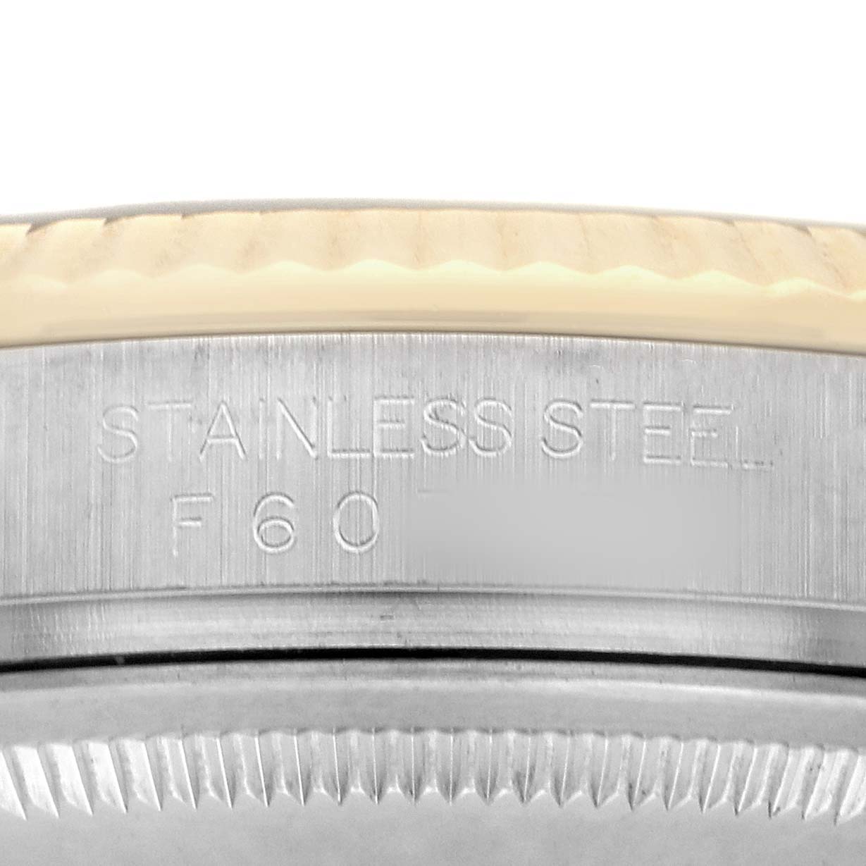 The image shows a close-up of the Rolex Datejust 116233 Men's Steel and Gold (two tone) Black Dial watch’s case edge, highlighting the stainless steel engraving.