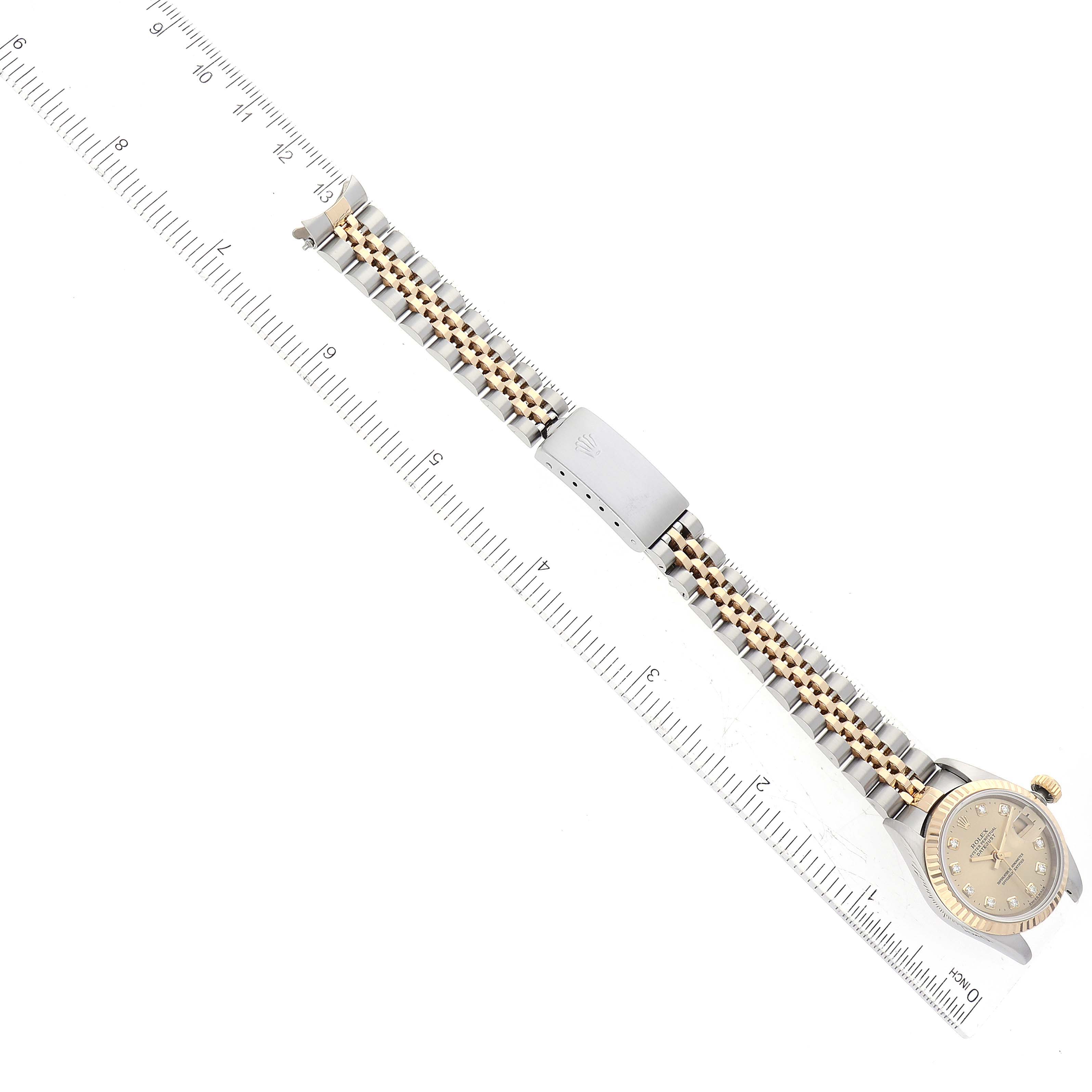 This top-down image shows the Rolex Datejust 69173 Women's Steel and Gold (two tone) Champagne Dial 69173 Women's Steel and Gold (two tone) Champagne Dial watch and its bracelet, positioned next to a ruler.