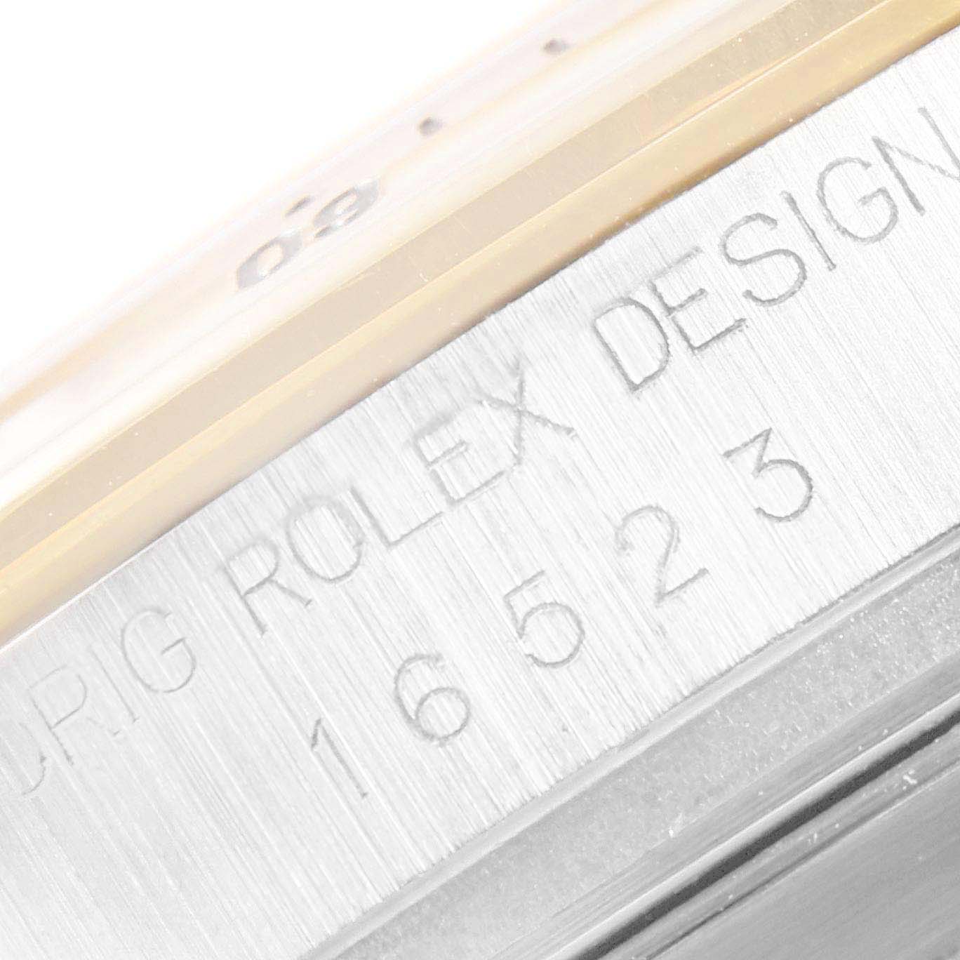 This close-up image shows the side of a Rolex Daytona 16523 Men
s Steel and Gold (two tone) White Dial 16523 Men
s Steel and Gold (two tone) White Dial watch, featuring engraved text and part of the bezel.