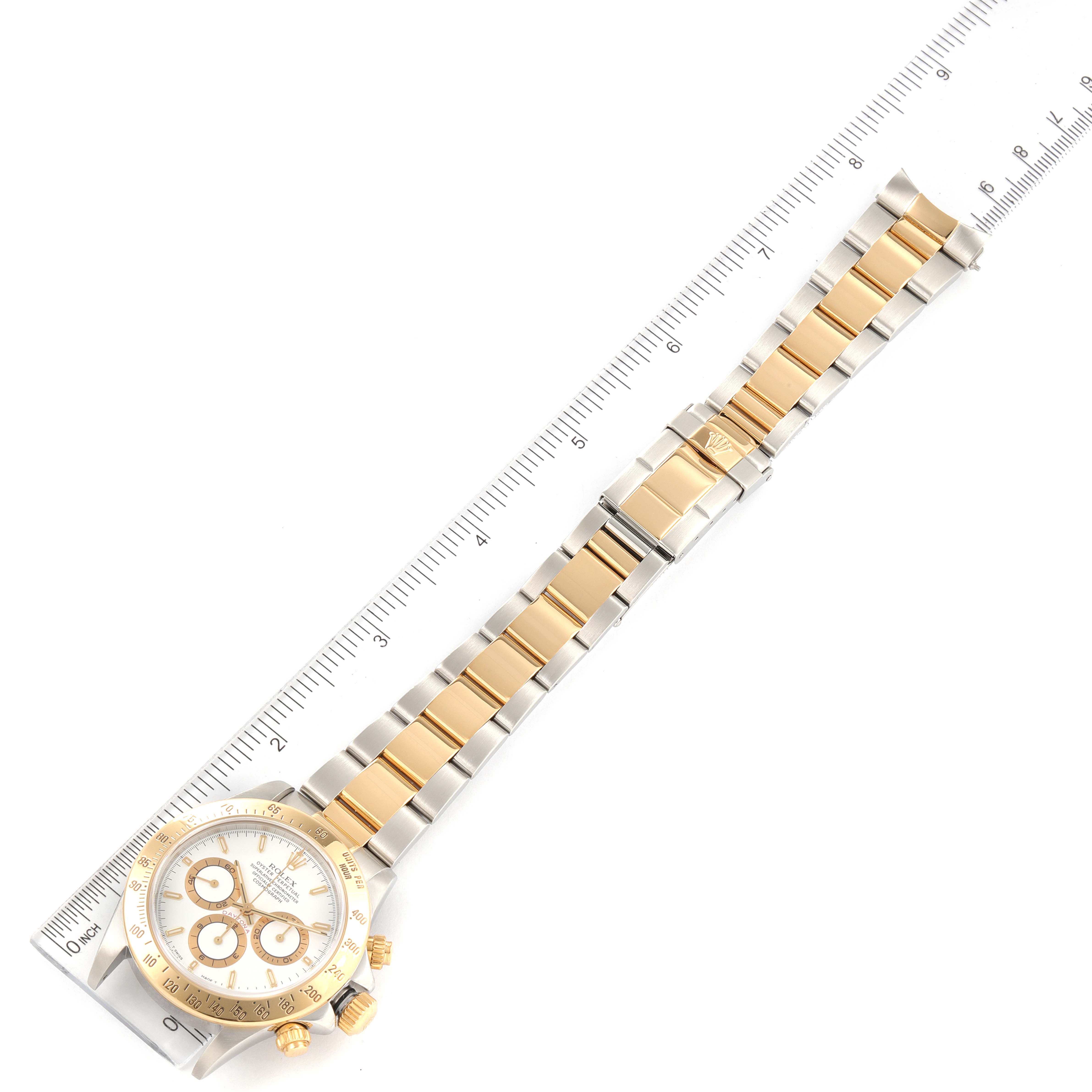 This image shows a top-down view of a Rolex Daytona 16523 Men
s Steel and Gold (two tone) White Dial 16523 Men
s Steel and Gold (two tone) White Dial watch, including the face, bezel, bracelet, and clasp, with a ruler beside it.