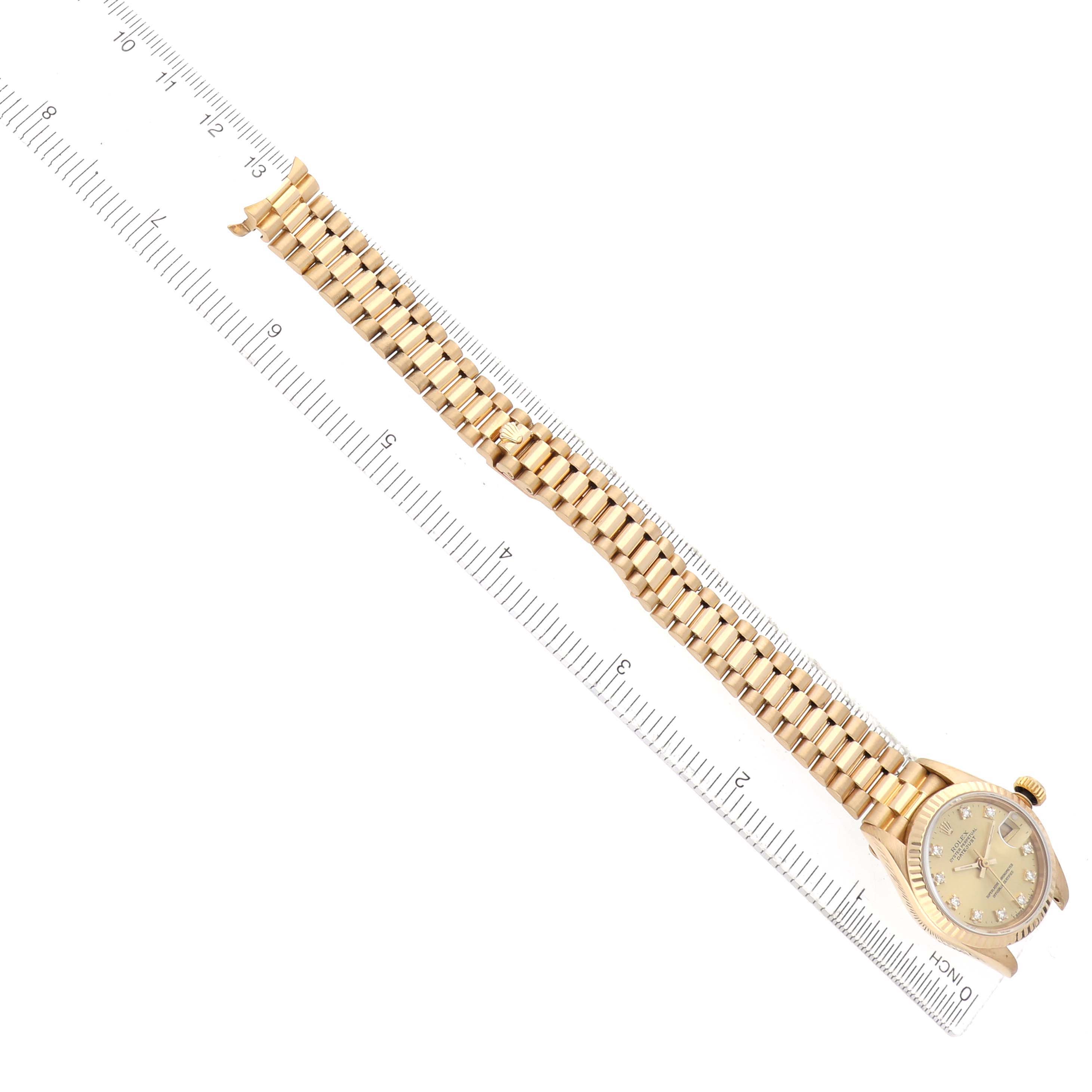 The Rolex President 69178 Women's Yellow Gold Champagne Dial model watch is shown from an overhead angle, displaying the full bracelet and dial, placed alongside a ruler.
