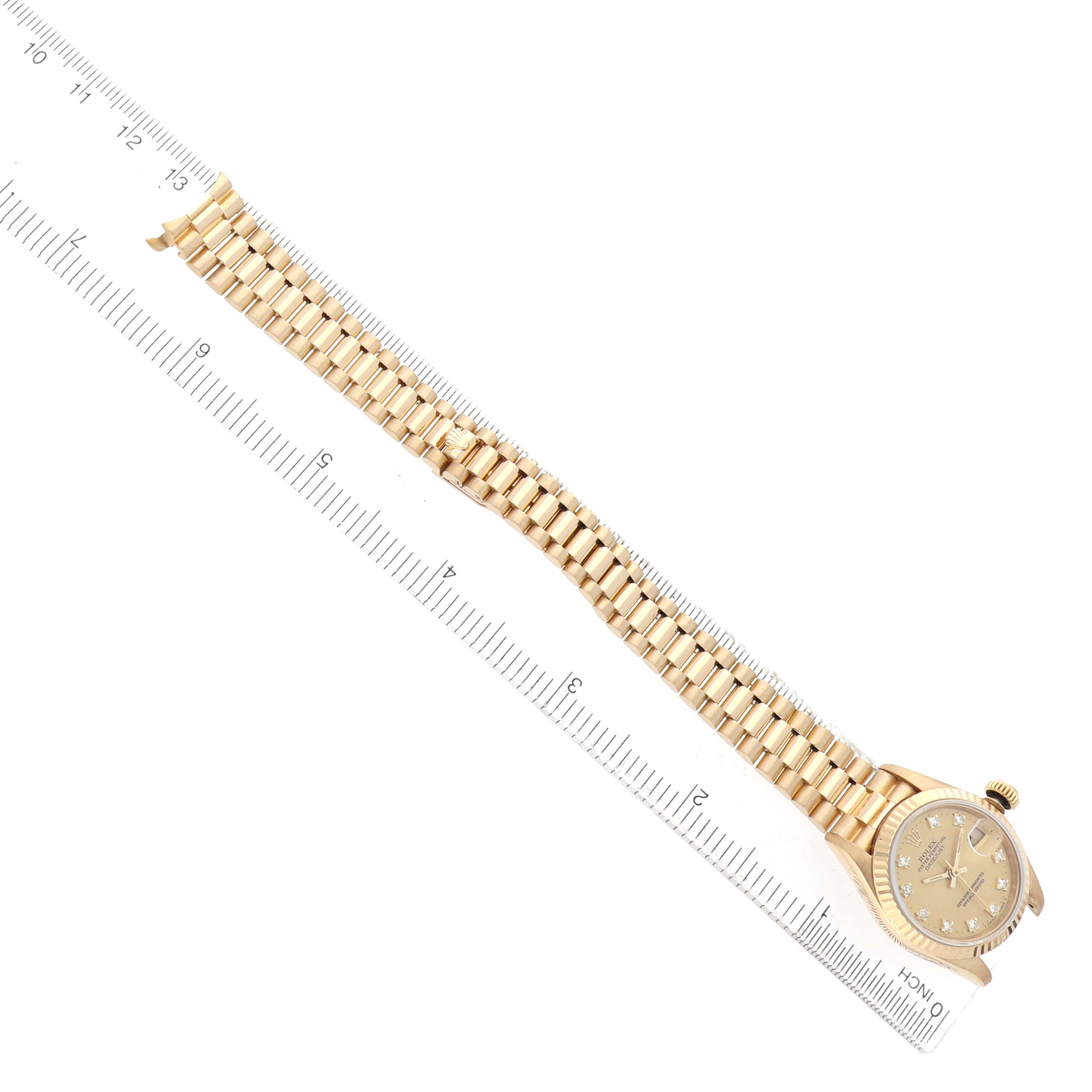 The Rolex President 69178 Women's Yellow Gold Champagne Dial model watch is shown from a top-down angle, displaying the bracelet, case, and dial alongside a ruler.