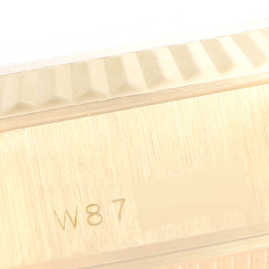 The image shows a close-up of the side of a Rolex President 69178 Women's Yellow Gold Champagne Dial 69178 Women's Yellow Gold Champagne Dial model watch, highlighting the fluted bezel and part of the case with an engraving.