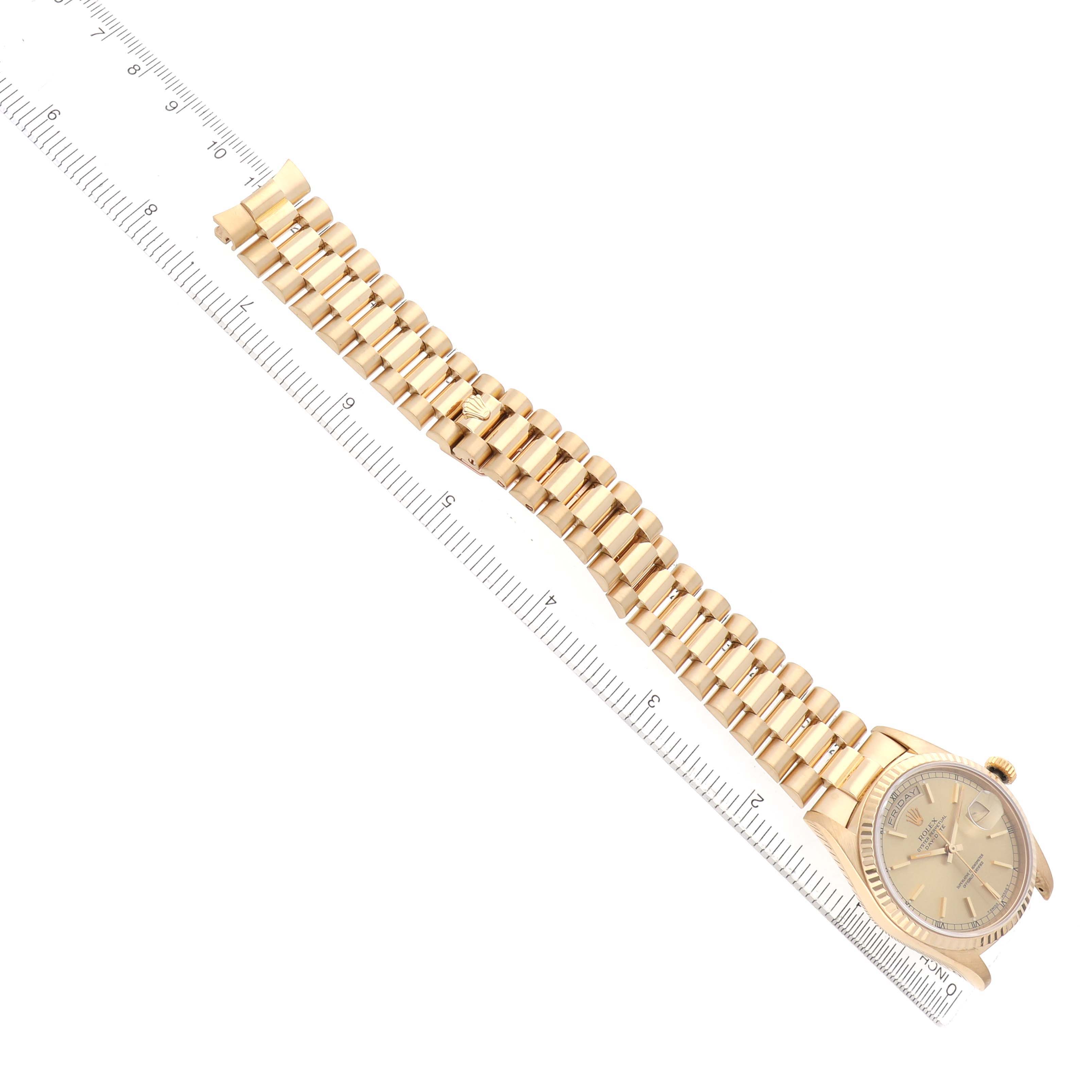 The Rolex President 18238 Men's Yellow Gold Champagne Dial watch is shown at an overhead angle, displaying its bracelet, case, and part of the dial with a ruler alongside.