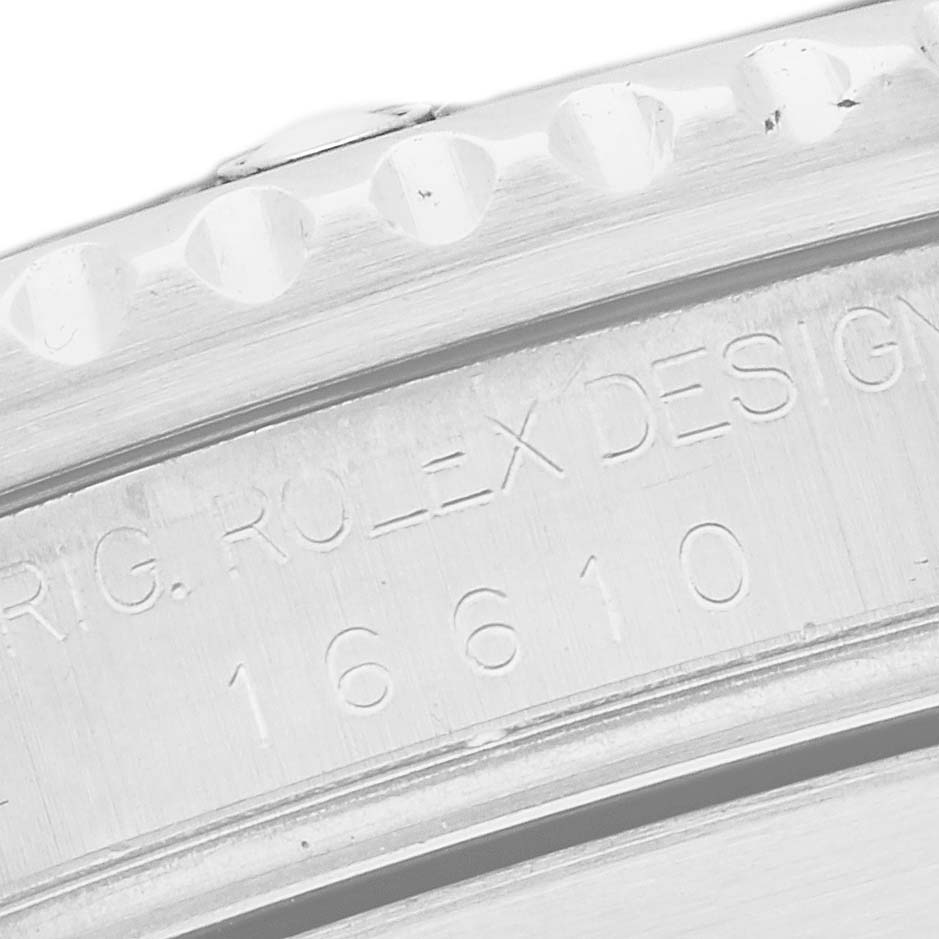 The image shows an angled close-up of the engraved inner bezel of a Rolex Submariner 16610 Men's Stainless Steel Black Dial watch, displaying model details.