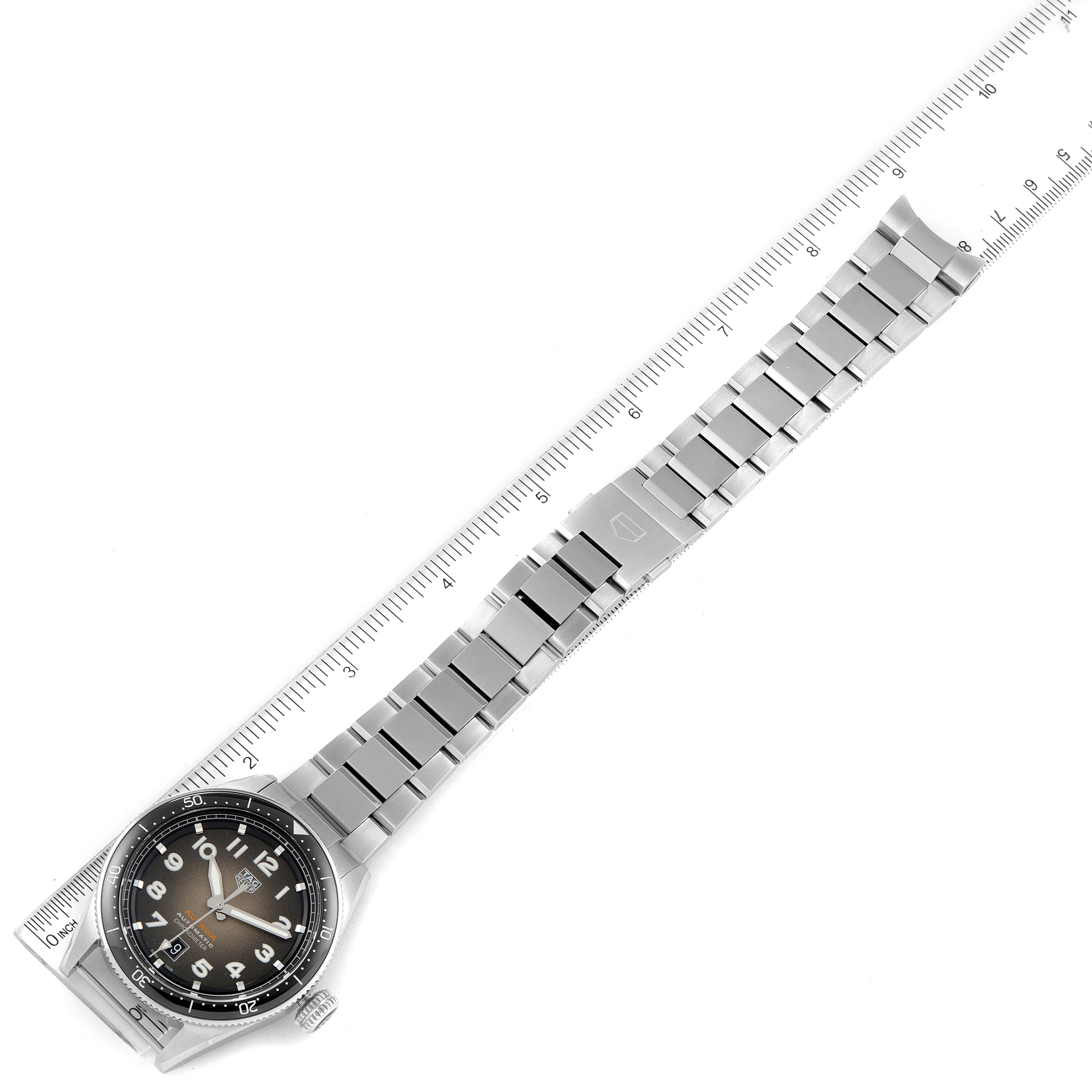 This image shows the full length of a Tag Heuer Autavia WBE5114.EB0173 Men's Stainless Steel Brown Dial WBE5114.EB0173 Men's Stainless Steel Brown Dial watch with its metal bracelet extended beside a ruler.