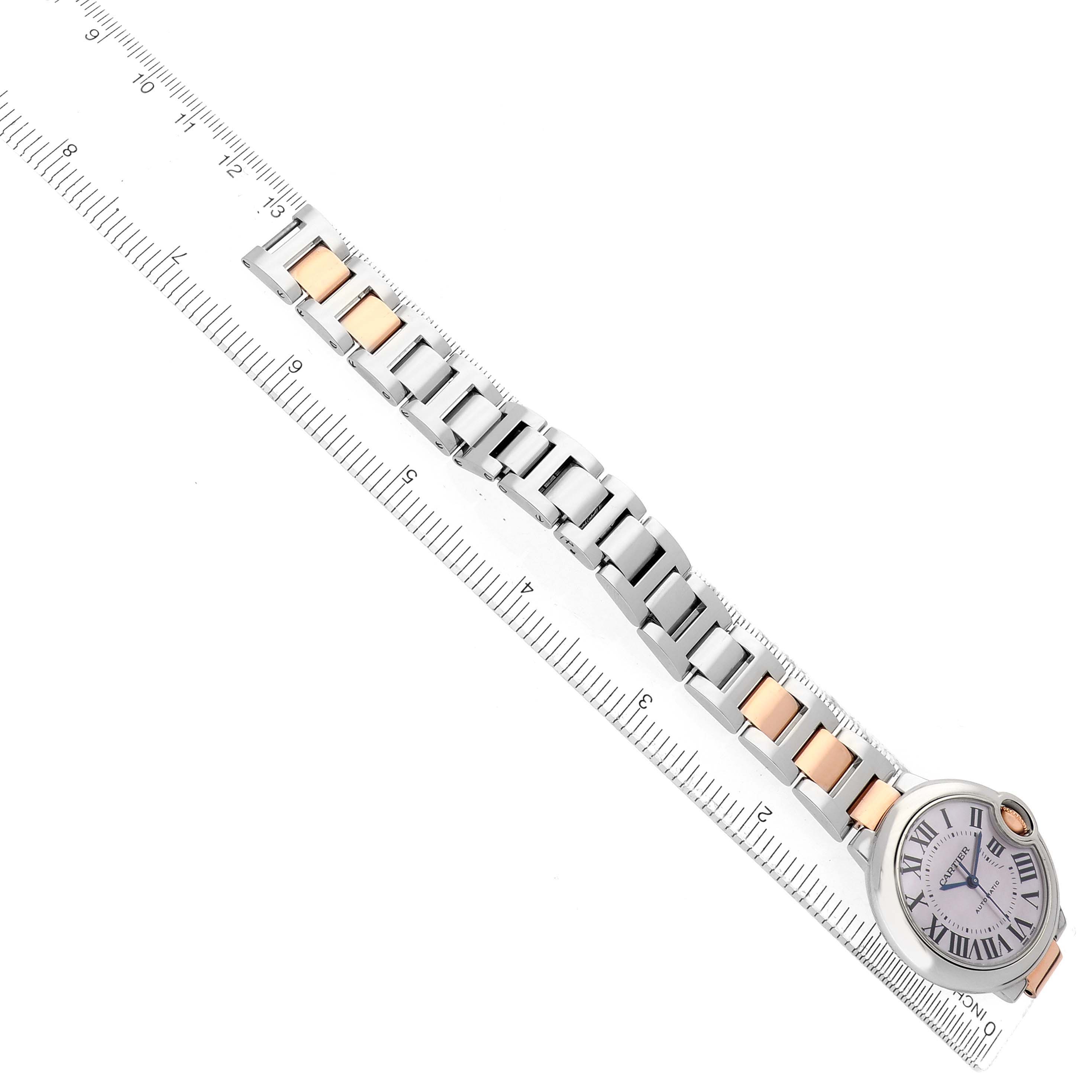 The Cartier Ballon Bleu W6920098 Women's Steel and Gold (two tone) Mother of Pearl Dial watch is shown from a top view with a focus on the strap and face, alongside a ruler.