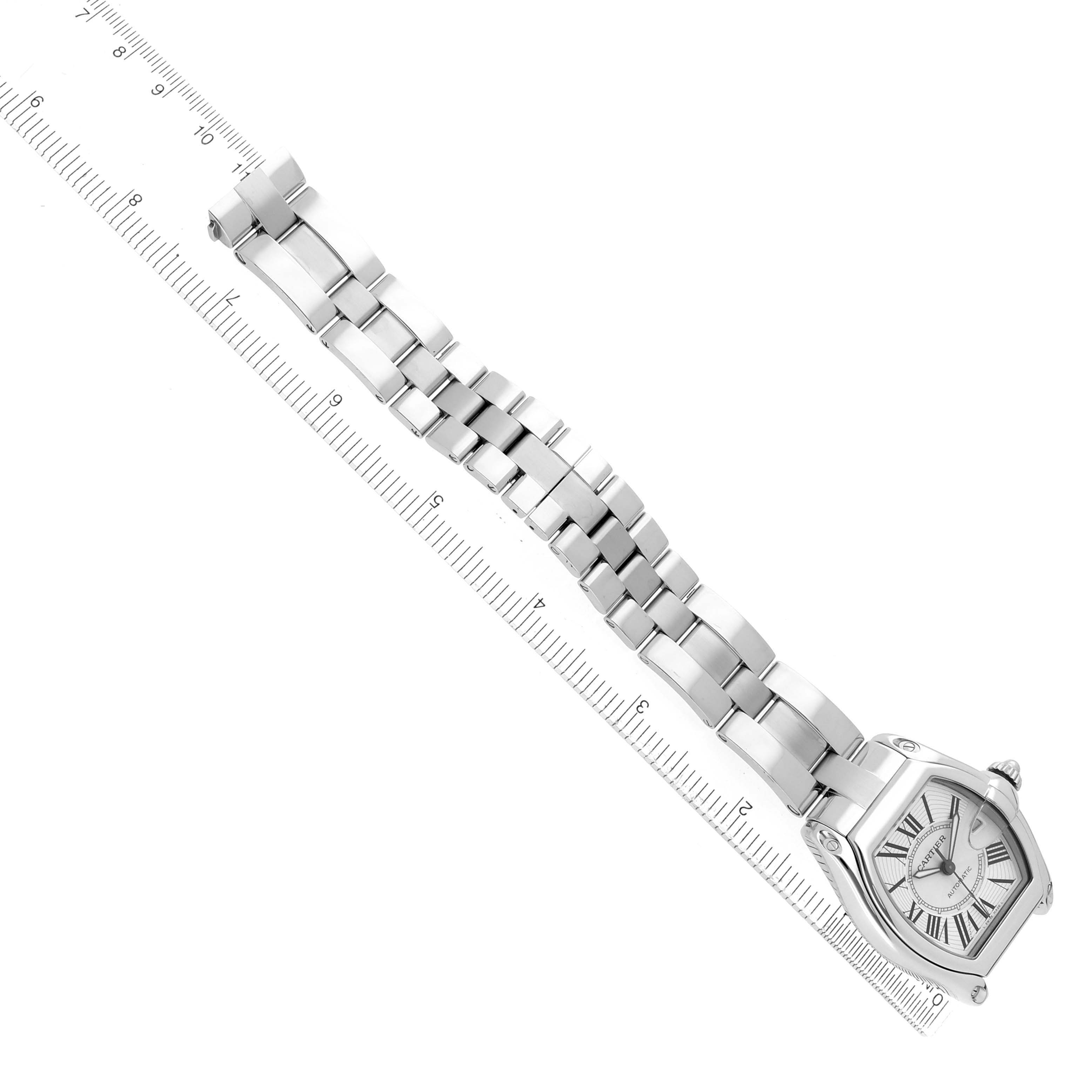 The Cartier Roadster W62025V3 Men's Stainless Steel Silver Dial watch is shown at an oblique angle, displaying the face and bracelet aligned with a ruler.