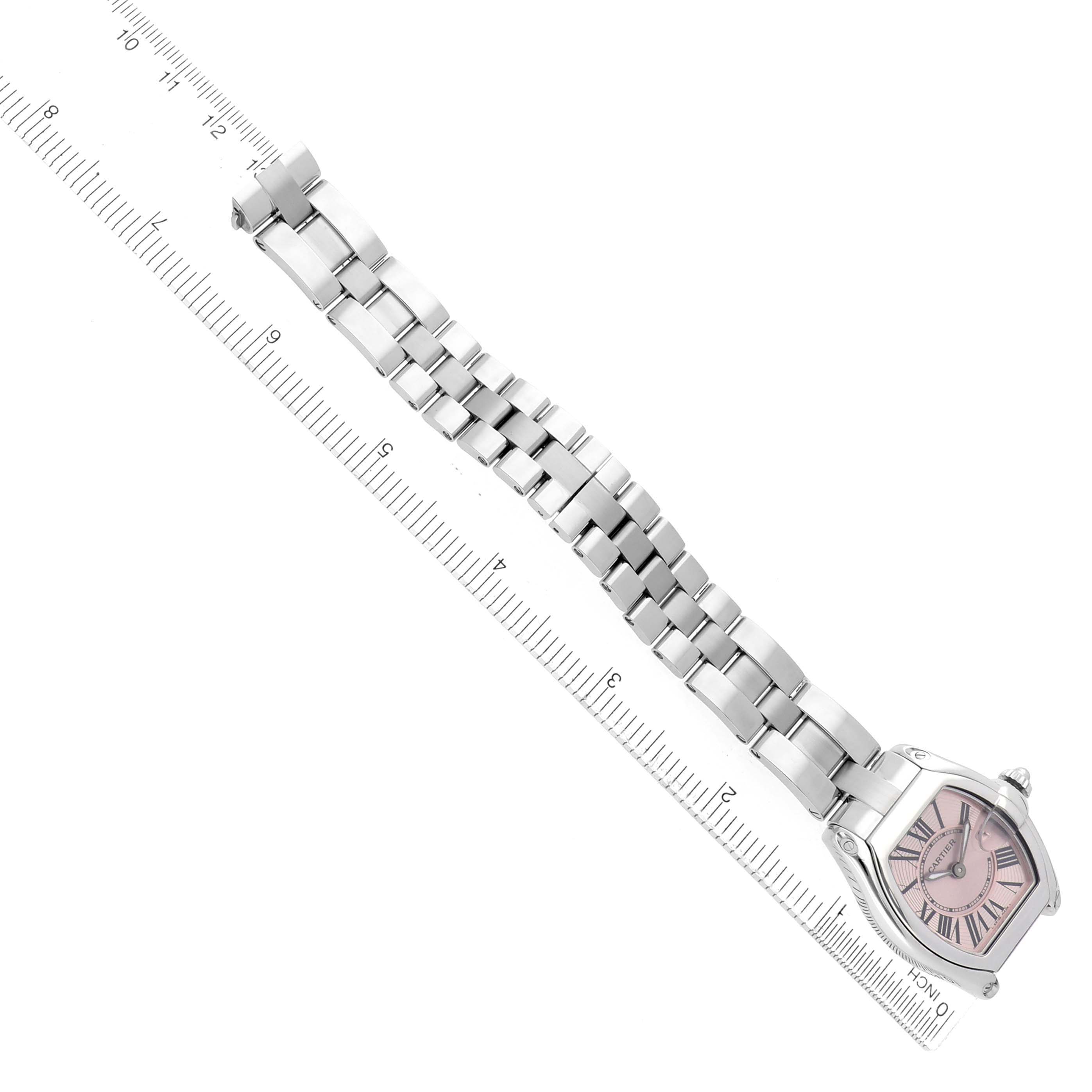 The Cartier Roadster W62017V3 Women's Stainless Steel Pink Dial watch is shown from a top-down angle, featuring the entire metal bracelet and face against a ruler backdrop.