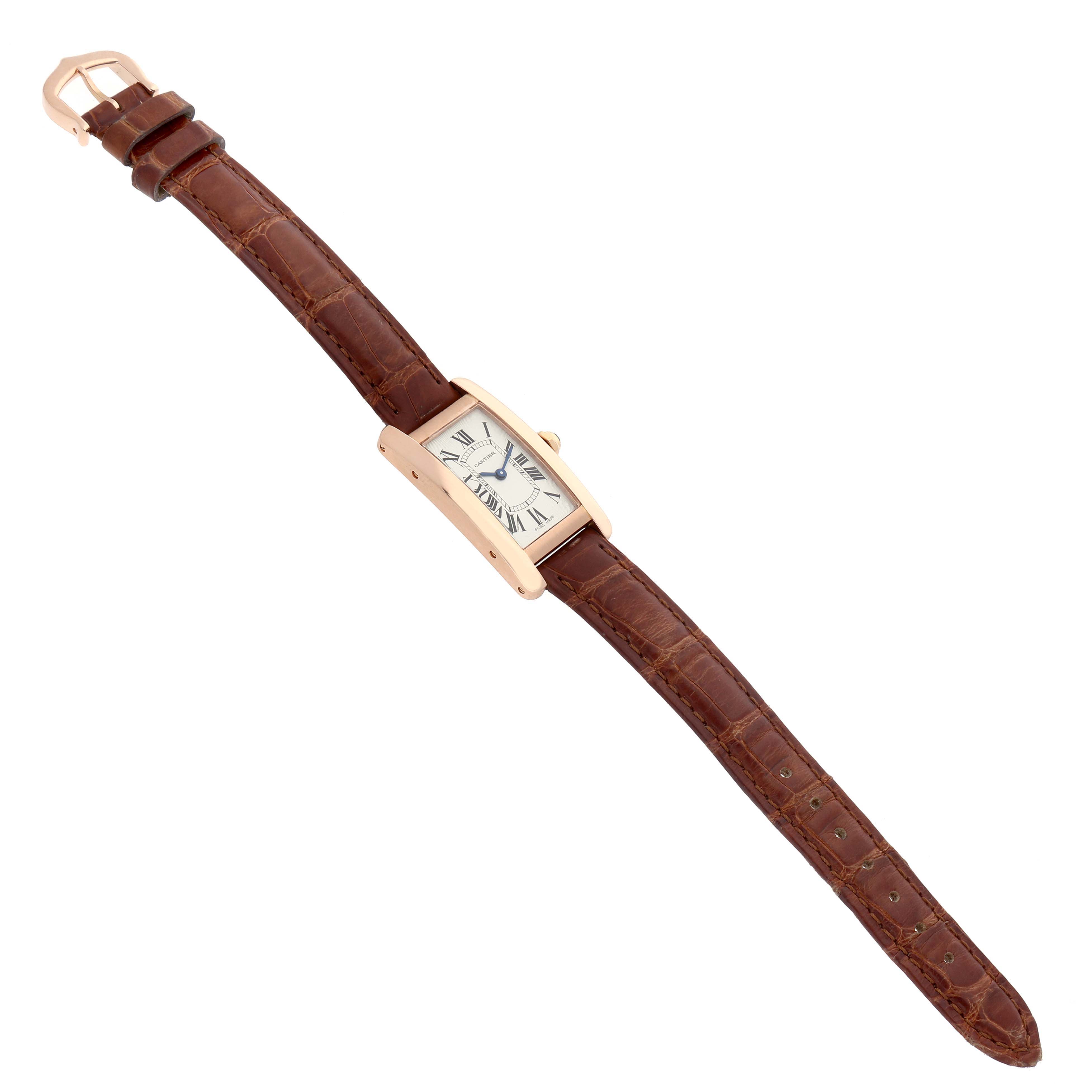 The Cartier Tank Américaine watch is shown in a top-down view, displaying the face, strap, buckle, and side profile.