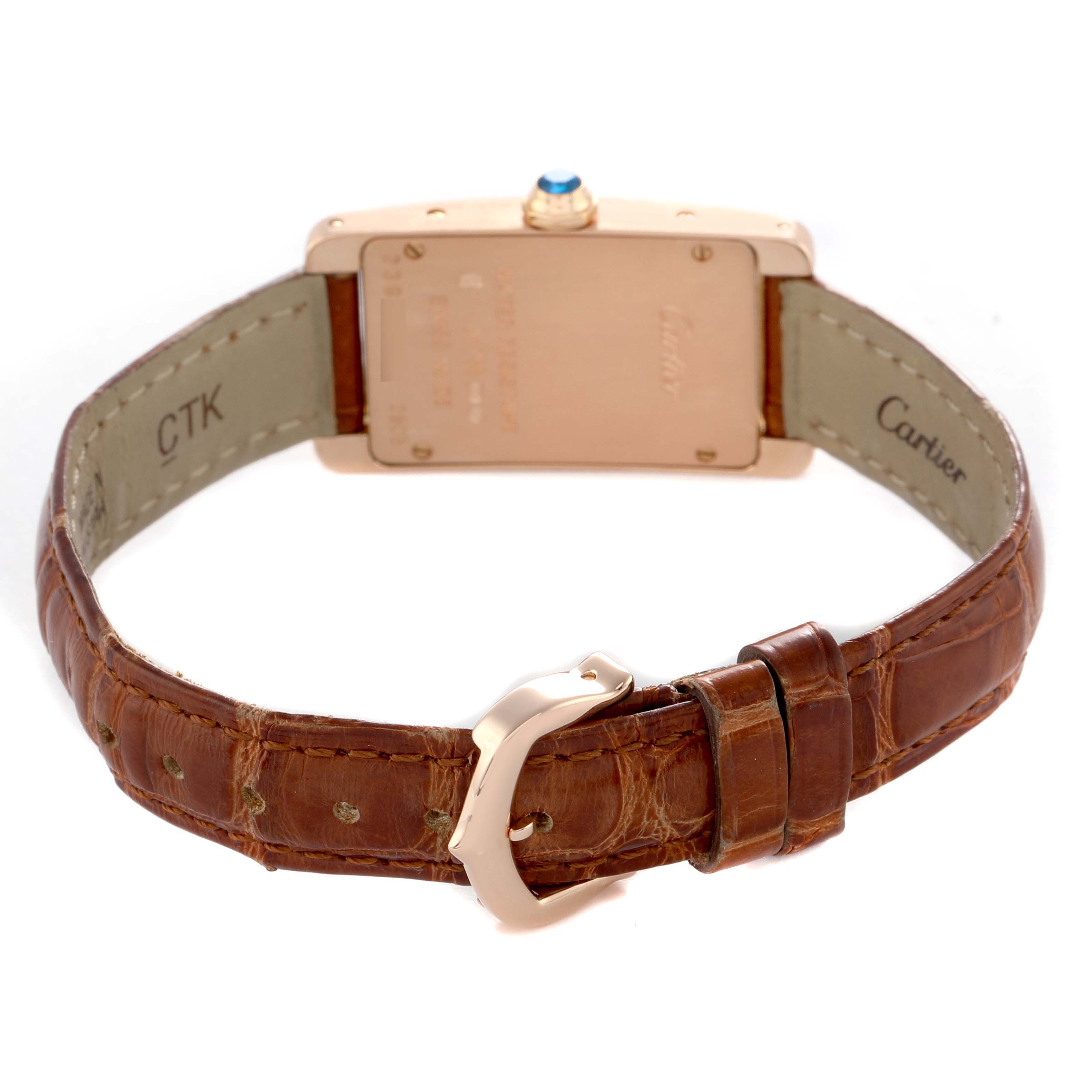 The Cartier Tank Américaine watch is shown from the back, highlighting its clasp, strap, case back, and crown with a blue cabochon.