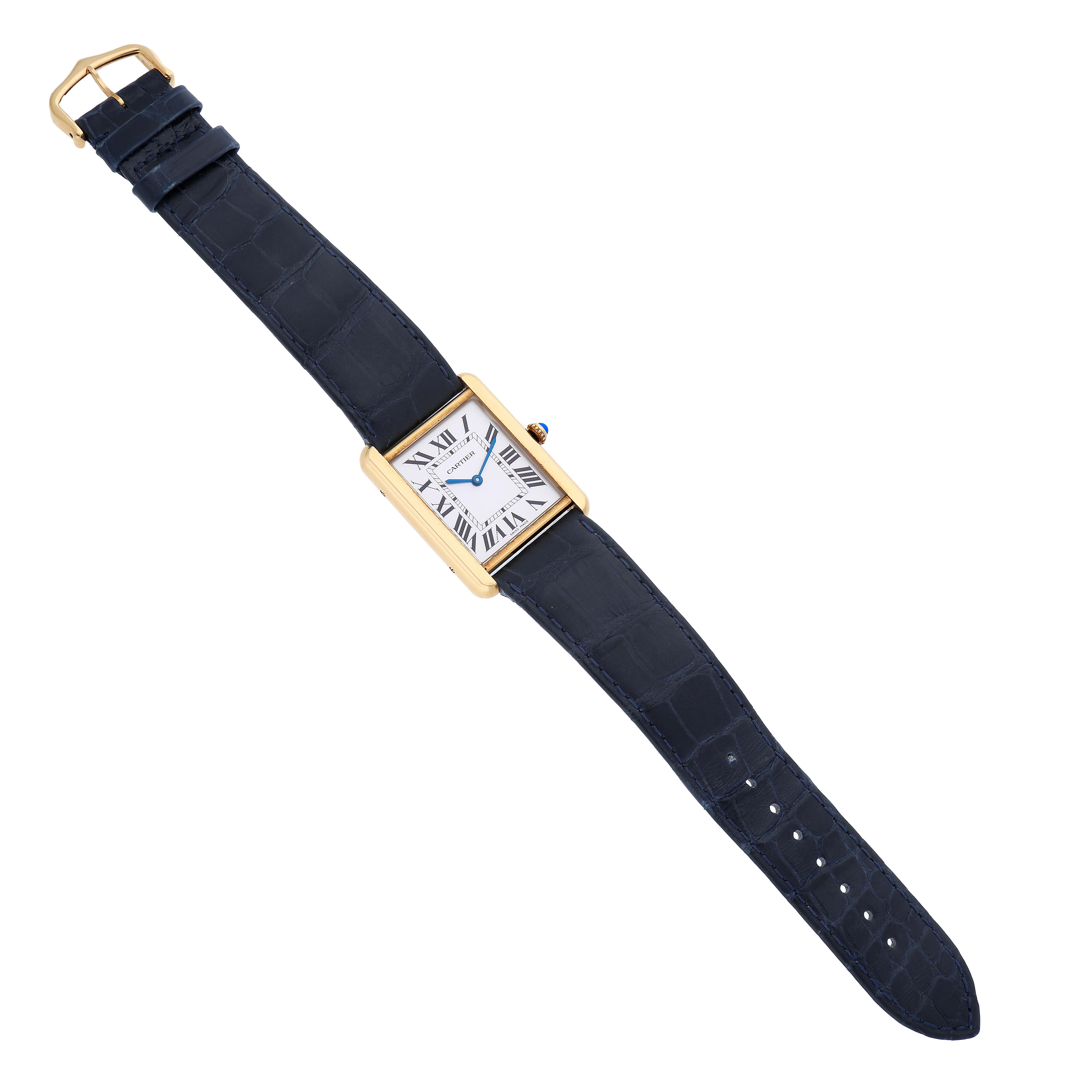 The Cartier Tank Solo W1018855 Men's Yellow Gold Silver Dial watch is shown flat, displaying its rectangular face, blue strap, and gold buckle from a top-down angle.