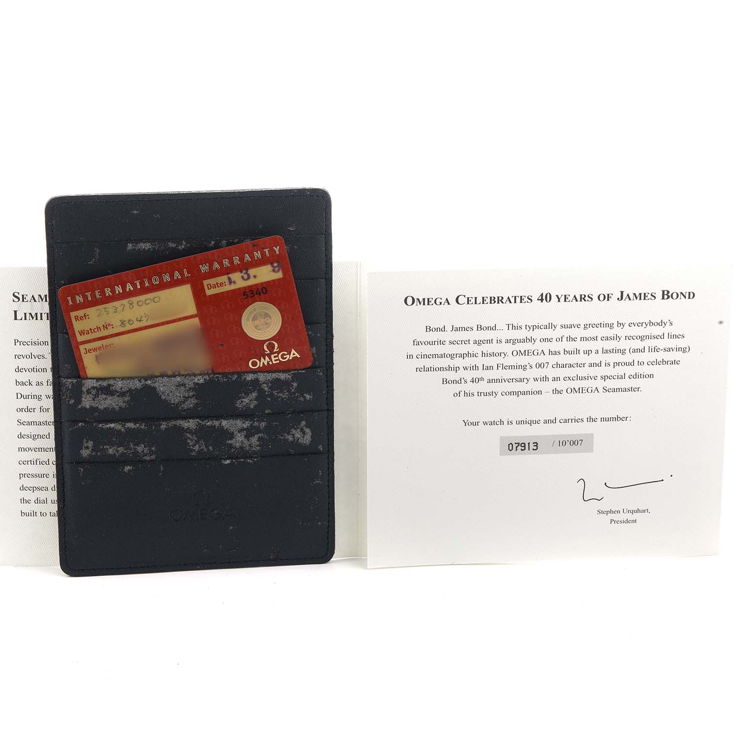 The image shows an Omega Seamaster 2537.80.00 Men's Stainless Steel Blue Dial warranty card inside a leather holder and a certificate celebrating 40 years of James Bond.