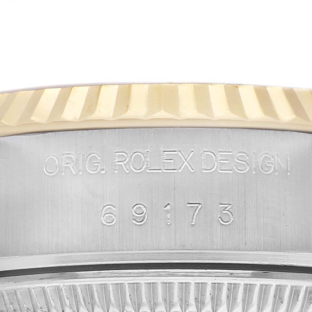 The image shows a close-up of the Rolex Datejust 69173 Women's Steel and Gold (two tone) Champagne Dial's engraved case side with a partial view of the fluted bezel.