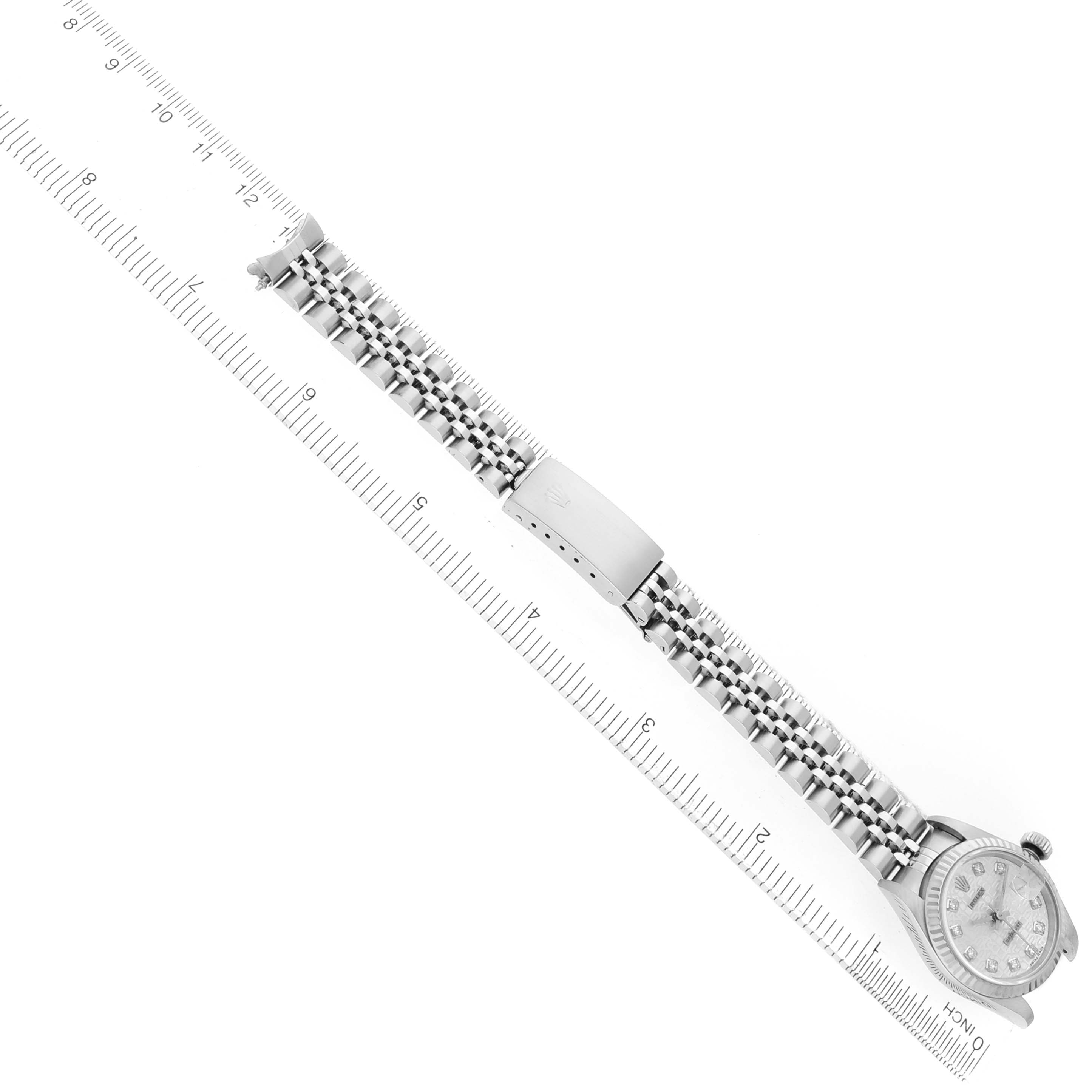 The Rolex Datejust 79174 Women's Stainless Steel Silver Dial watch is shown from a top view, displaying the face, bracelet, and clasp alongside a ruler for scale.