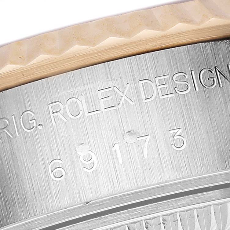 The image shows a close-up of the Rolex Datejust 69173 Women's Steel and Gold (two tone) Black Dial 69173 Women's Steel and Gold (two tone) Black Dial's case side with engraved text and part of the bezel.