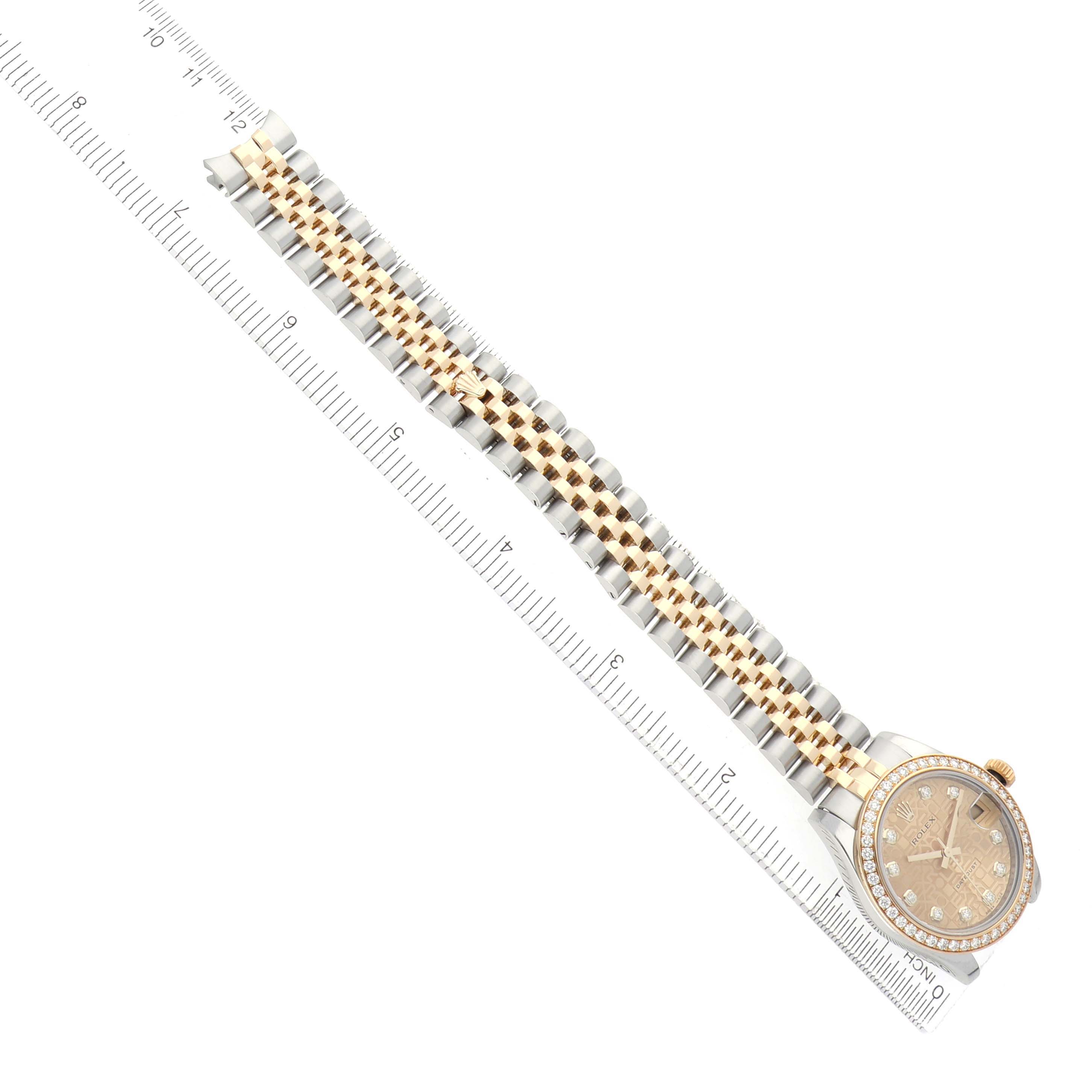The Rolex Mid-Size M178383-0008 Women's Steel and Gold (two tone) Champagne Dial model is shown from a top-down angle, highlighting the face, bezel, and two-tone bracelet alongside a ruler.