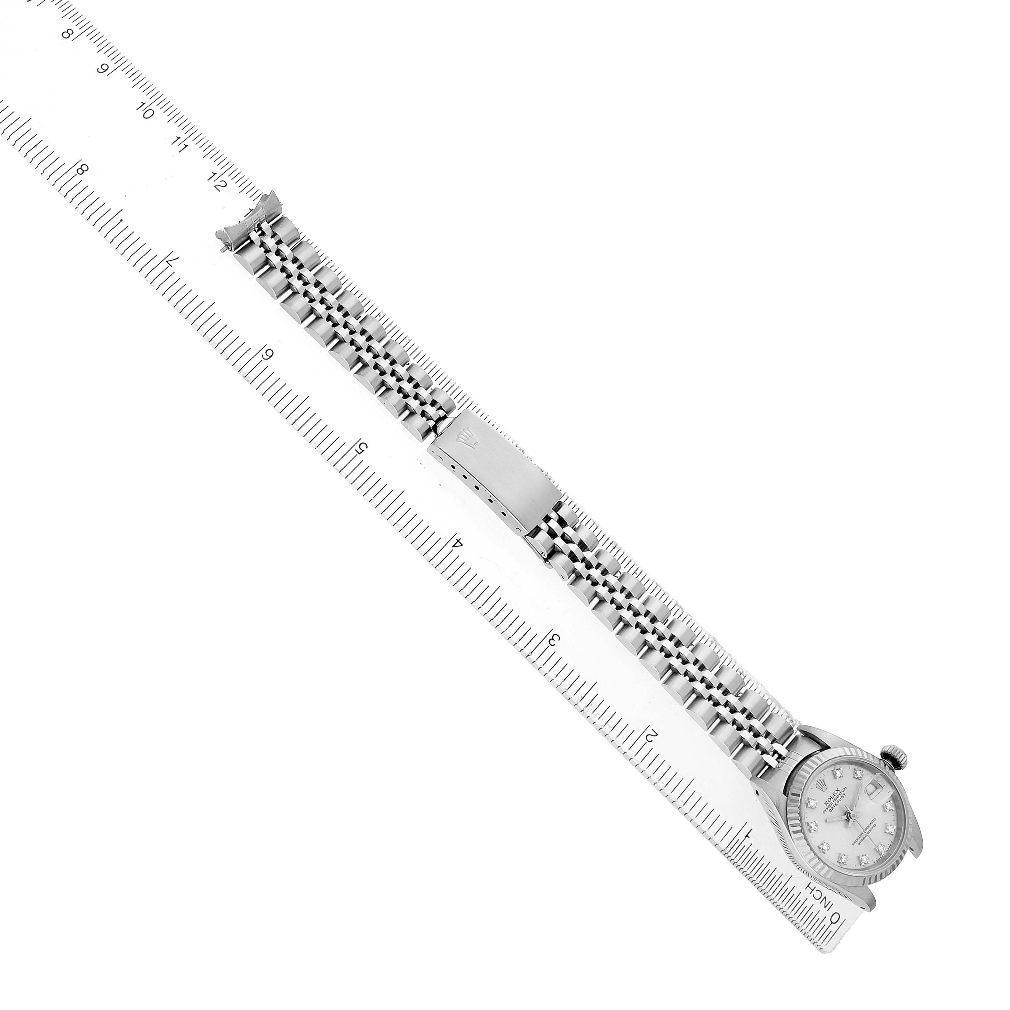 The Rolex Datejust 69174 Women's Stainless Steel Silver Dial watch is shown from a top view, displaying its face, bracelet, and clasp laid alongside a ruler for scale.