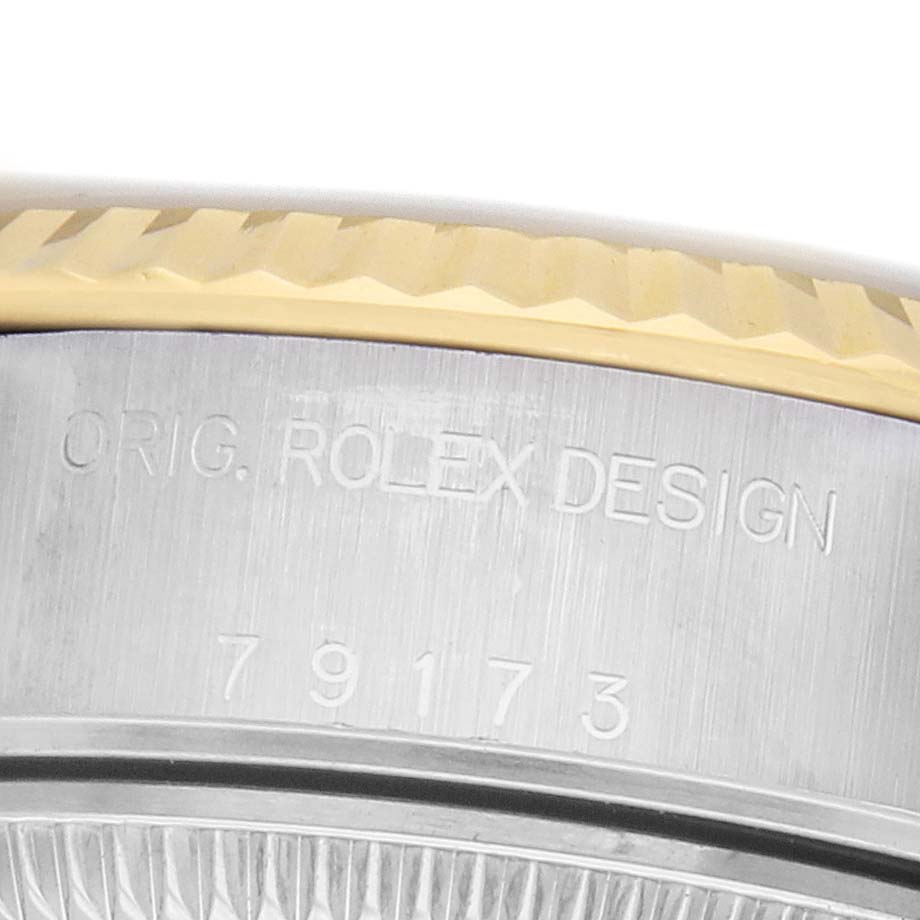 The image shows a close-up of the Rolex Datejust 79173 Women's Steel and Gold (two tone) Silver Dial's side, featuring the fluted bezel and engraved serial number.