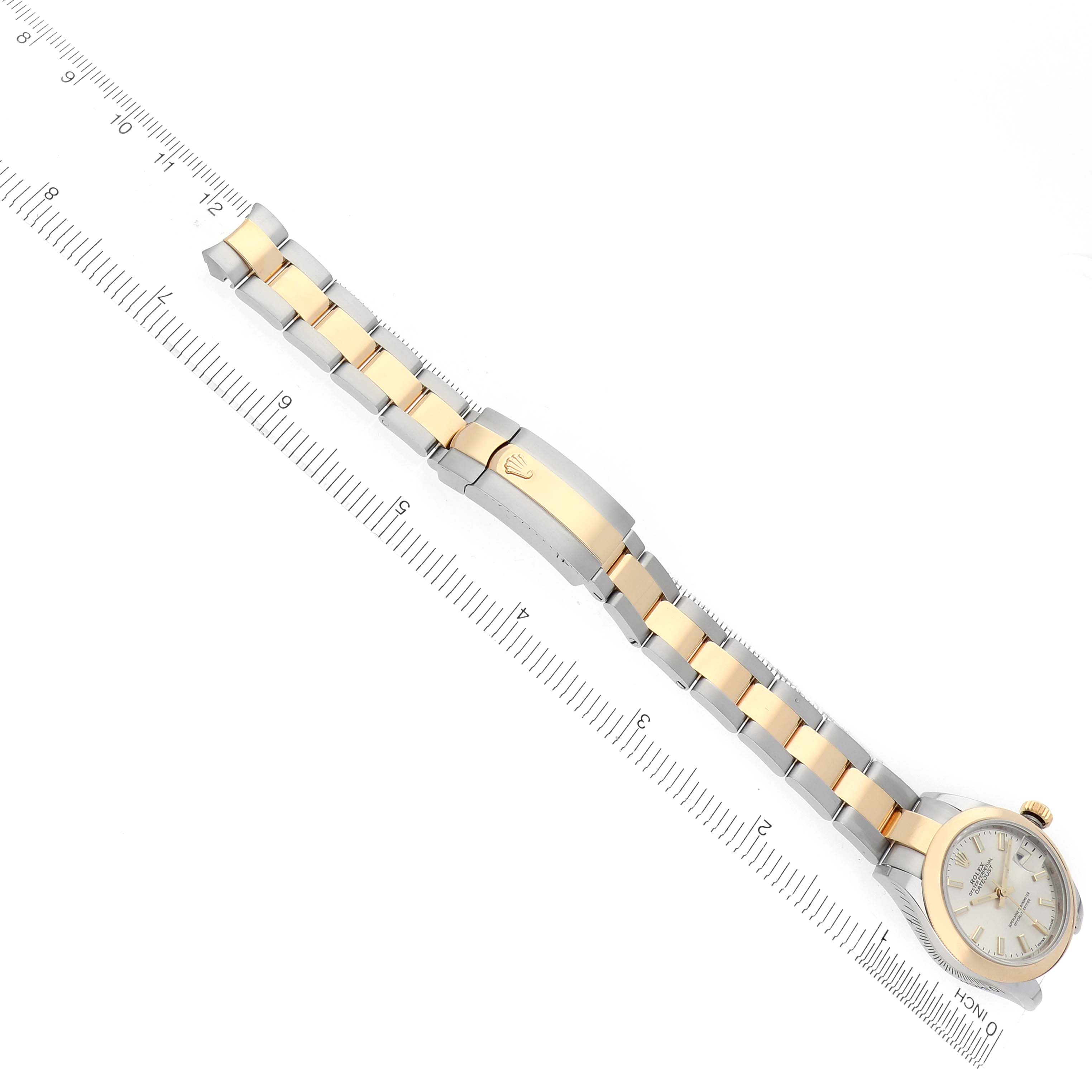 The Rolex Datejust 279163 Women's Steel and Gold (two tone) Silver Dial is shown from an aerial angle, displaying the full bracelet, clasp, and watch face alongside a ruler.