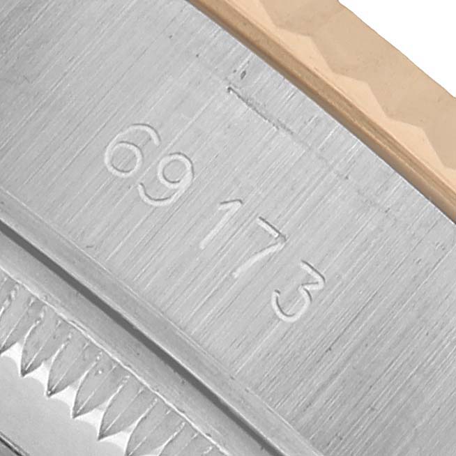 This image shows a close-up of the Rolex Datejust 69173 Women's Steel and Gold (two tone) White Dial model, focusing on its engraved case edge and the serial number.