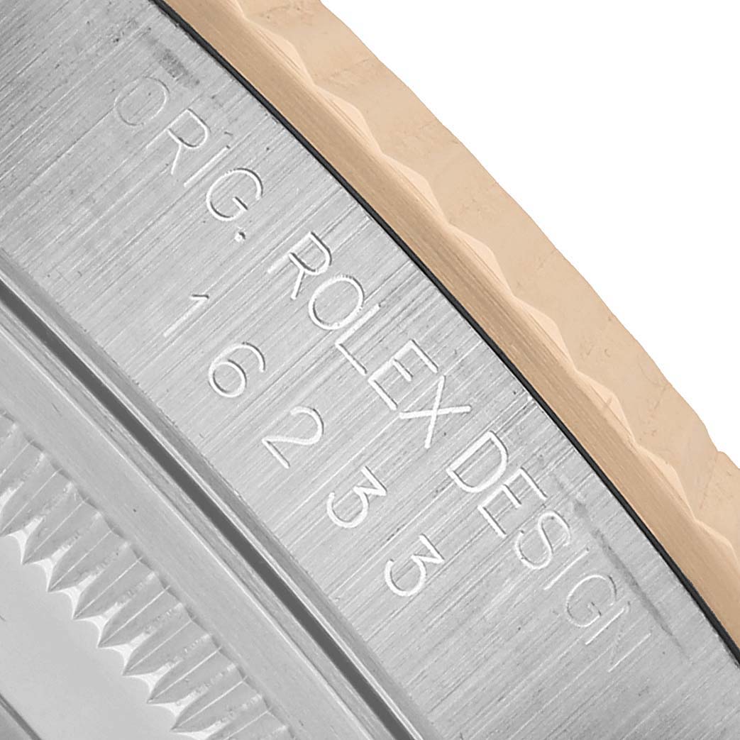 The angle shows a close-up of the side of a Rolex Datejust 16233 Men's Steel and Gold (two tone) White Dial, highlighting engraved text and the edge of the bezel.