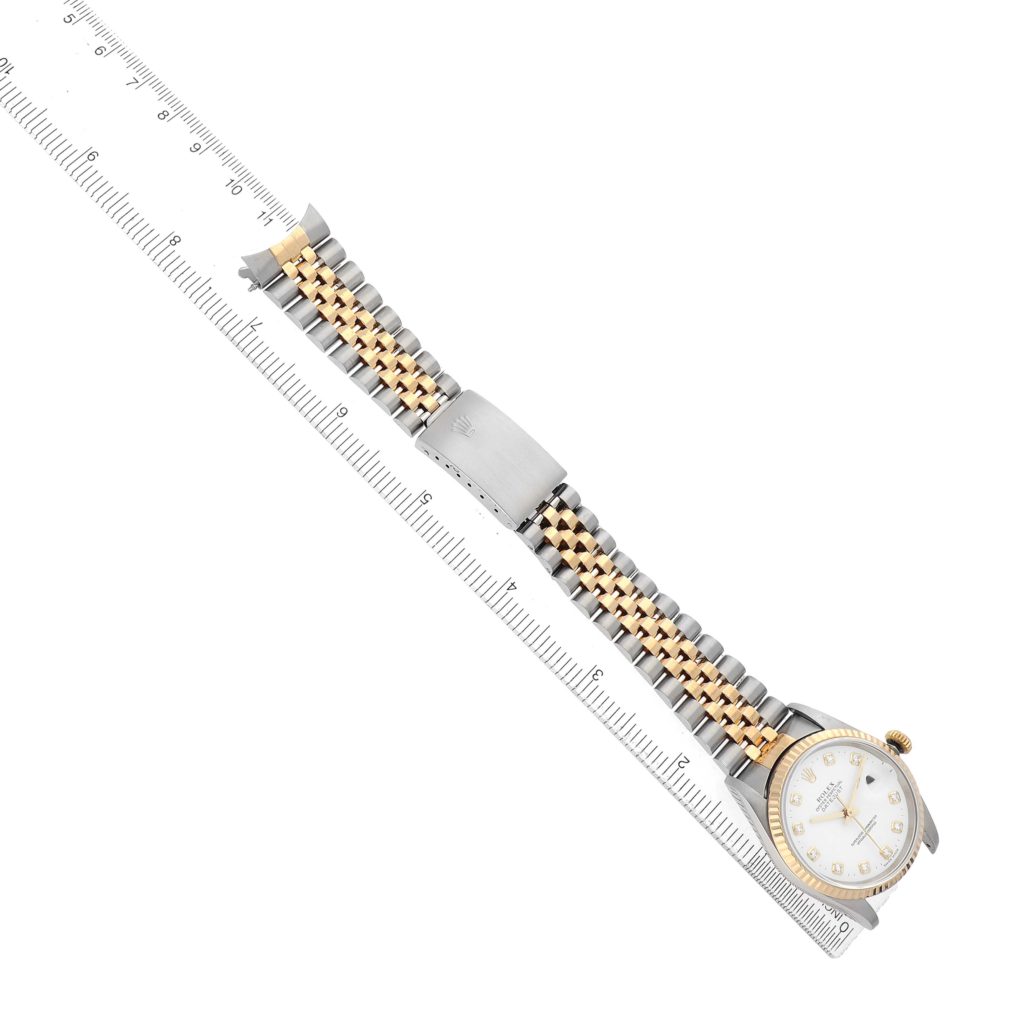 The Rolex Datejust 16233 Men's Steel and Gold (two tone) White Dial watch is shown from above, displaying the bracelet, clasp, and face next to a ruler.