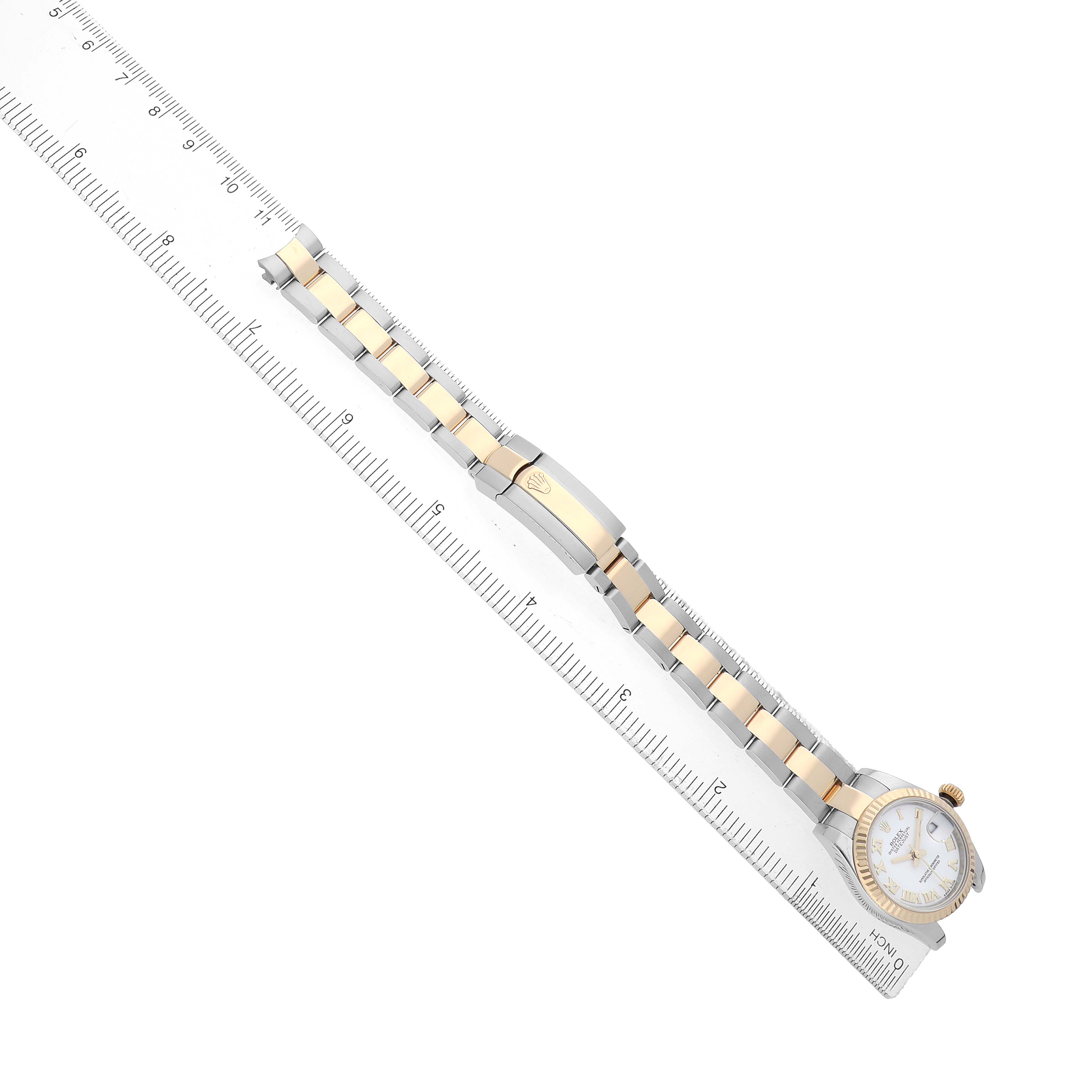 The Rolex Datejust 179173 Women's Steel and Gold (two tone) White Dial watch is shown from a top-down angle alongside a ruler, highlighting its bracelet and face.
