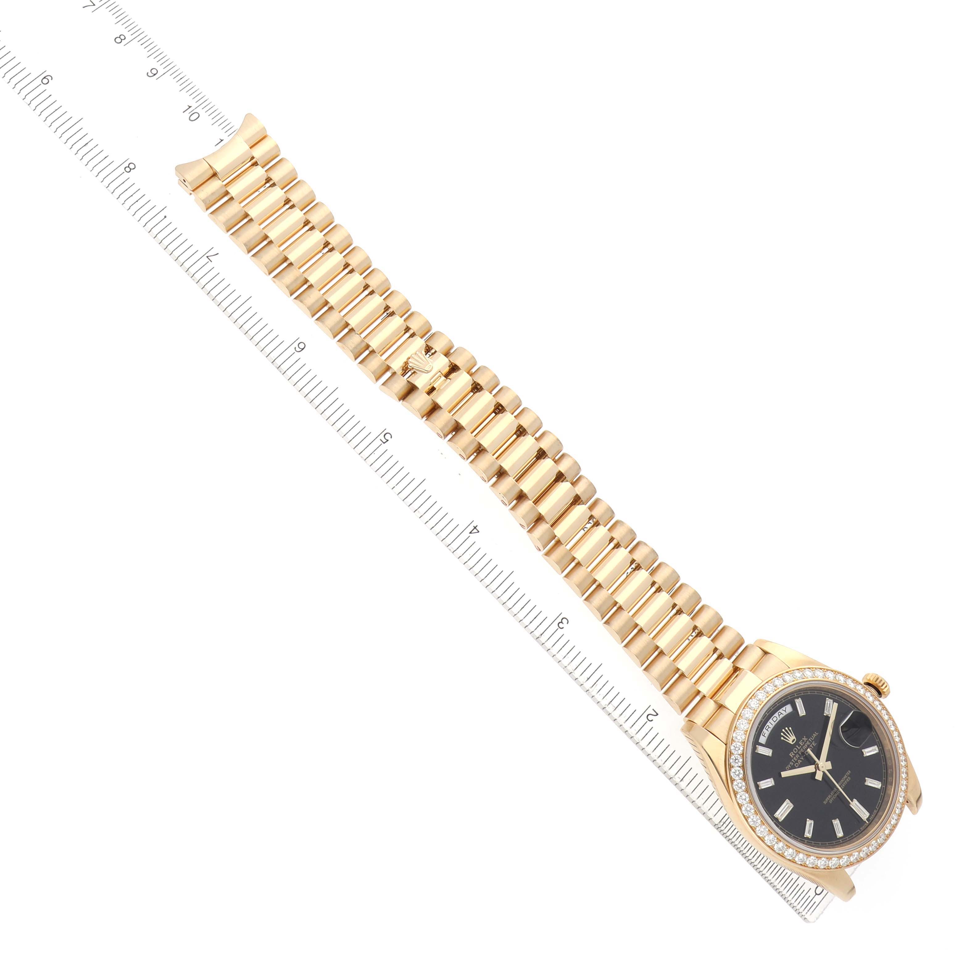 The Rolex President 228348 Men's Yellow Gold Black Dial watch is shown at an angled top-down view, highlighting the bracelet and dial with a ruler for scale.