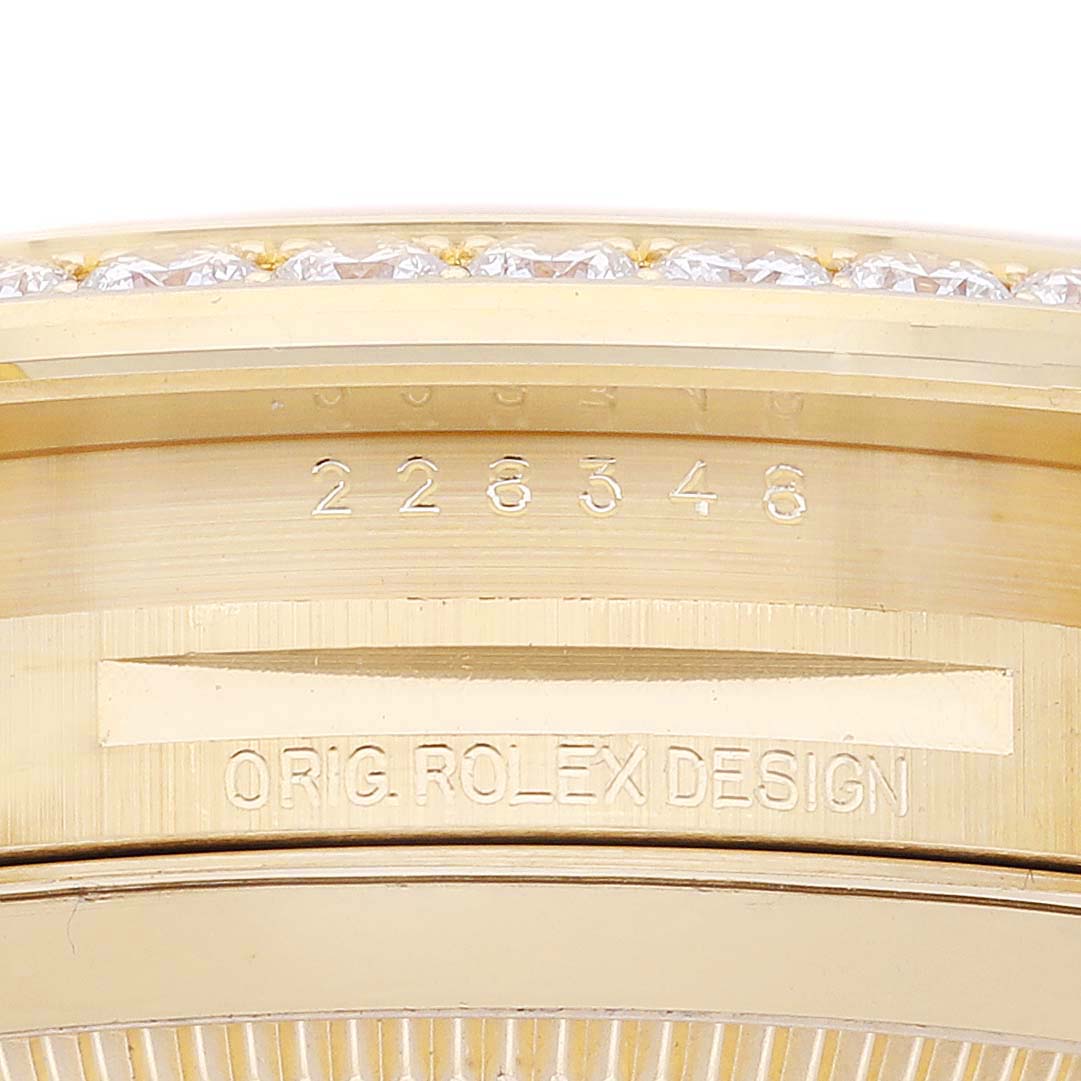 The image shows a close-up of the side of the Rolex President 228348RBR Men's Yellow Gold Champagne Dial 228348RBR Men's Yellow Gold Champagne Dial watch's case with the model number and "ORIG ROLEX DESIGN" engraving.