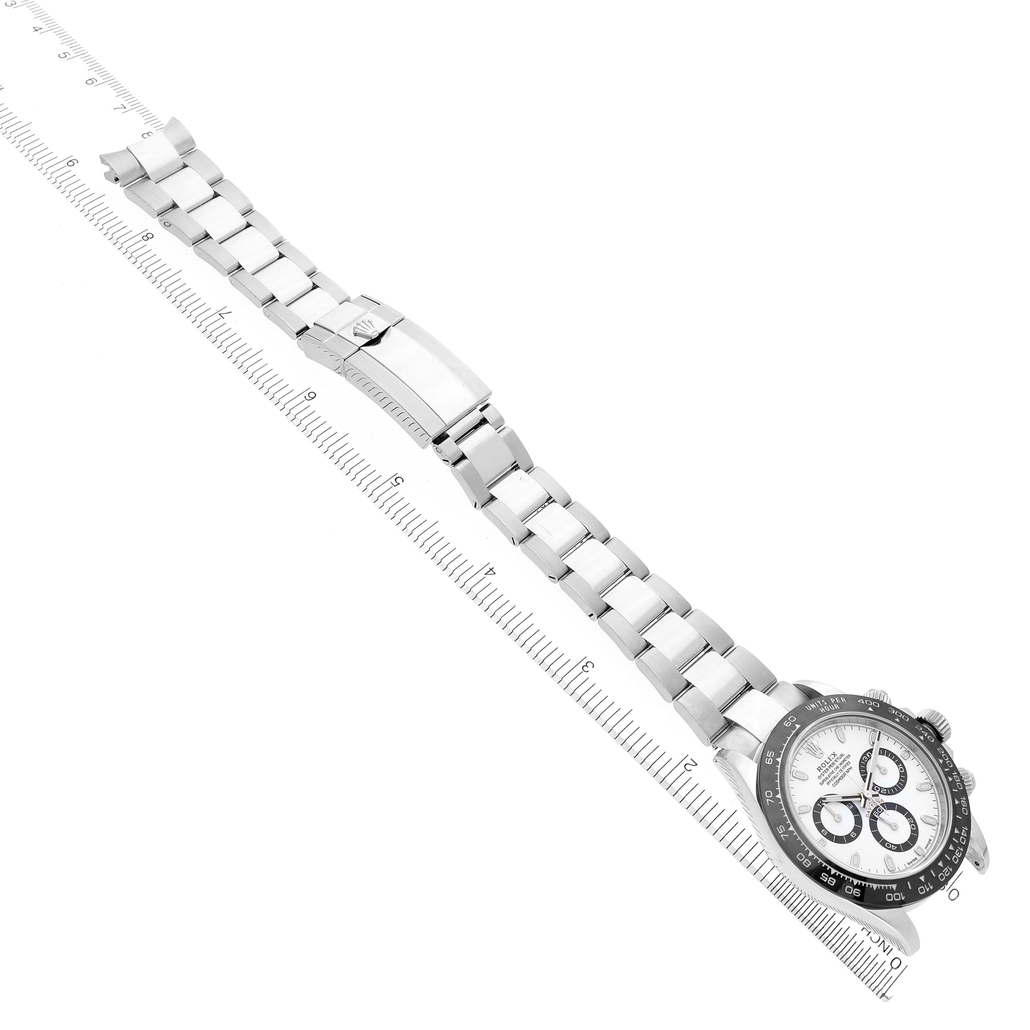 The Rolex Daytona 116500LN Men's Stainless Steel White Dial 116500LN Men's Stainless Steel White Dial watch is shown from a top angle, displaying its face and full metal bracelet alongside a ruler.