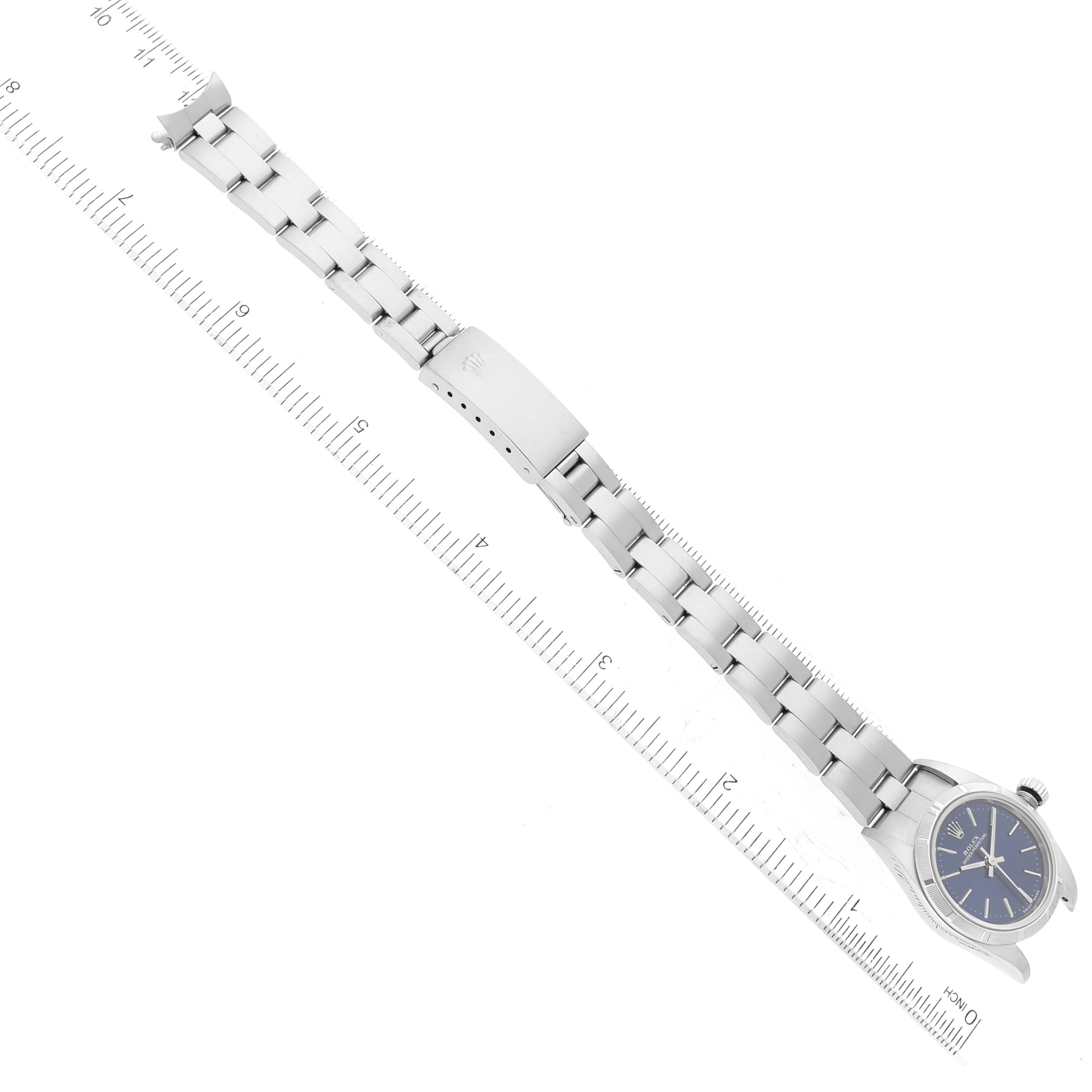 This image shows the Rolex Oyster Perpetual 76030 Women's Stainless Steel Blue Dial 76030 Women's Stainless Steel Blue Dial watch laid flat with its bracelet extended and measured against a ruler.