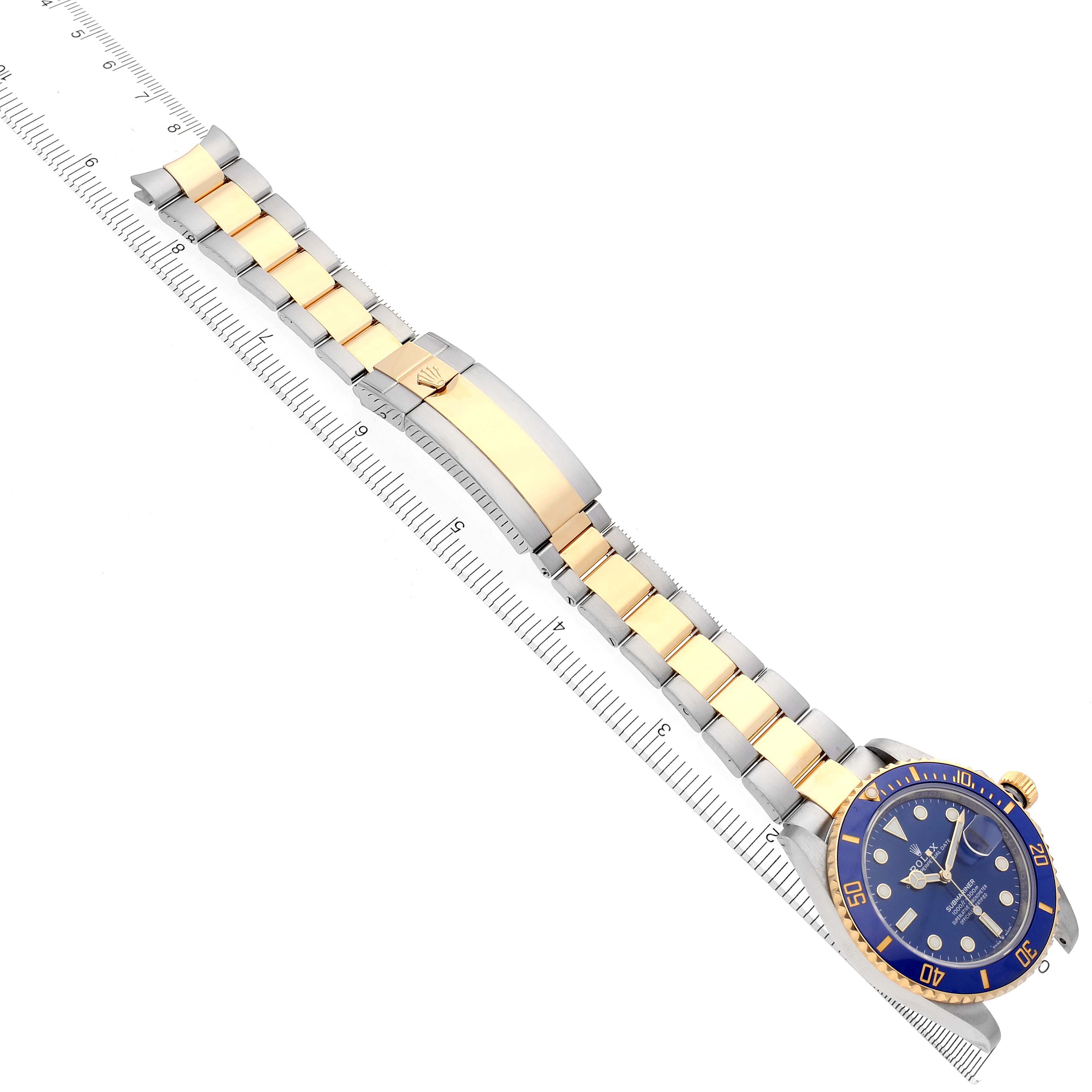 The Rolex Submariner 126613LB Men's Steel and Gold (two tone) Blue Dial 126613LB Men's Steel and Gold (two tone) Blue Dial watch is shown from a top angle, displaying the bracelet and face beside a ruler.
