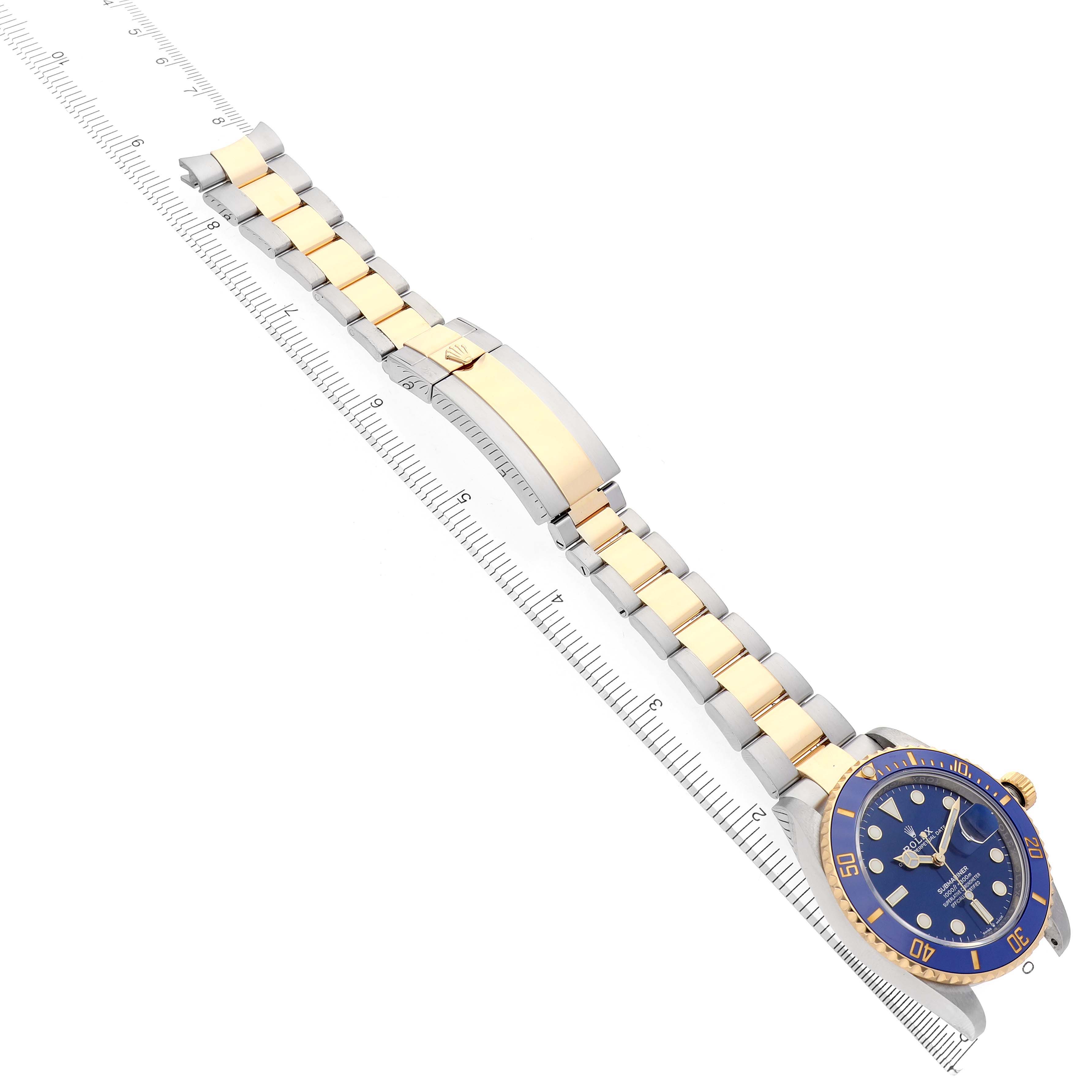 The image shows a Rolex Submariner 126613LB Men's Steel and Gold (two tone) Blue Dial 126613LB Men's Steel and Gold (two tone) Blue Dial watch from a top angle, displaying the full bracelet and dial, placed over a ruler.