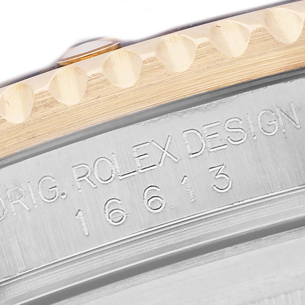 The image shows a close-up of the Rolex Submariner 16613 Men's Steel and Gold (two tone) Silver Dial's engraved side and part of the bezel.