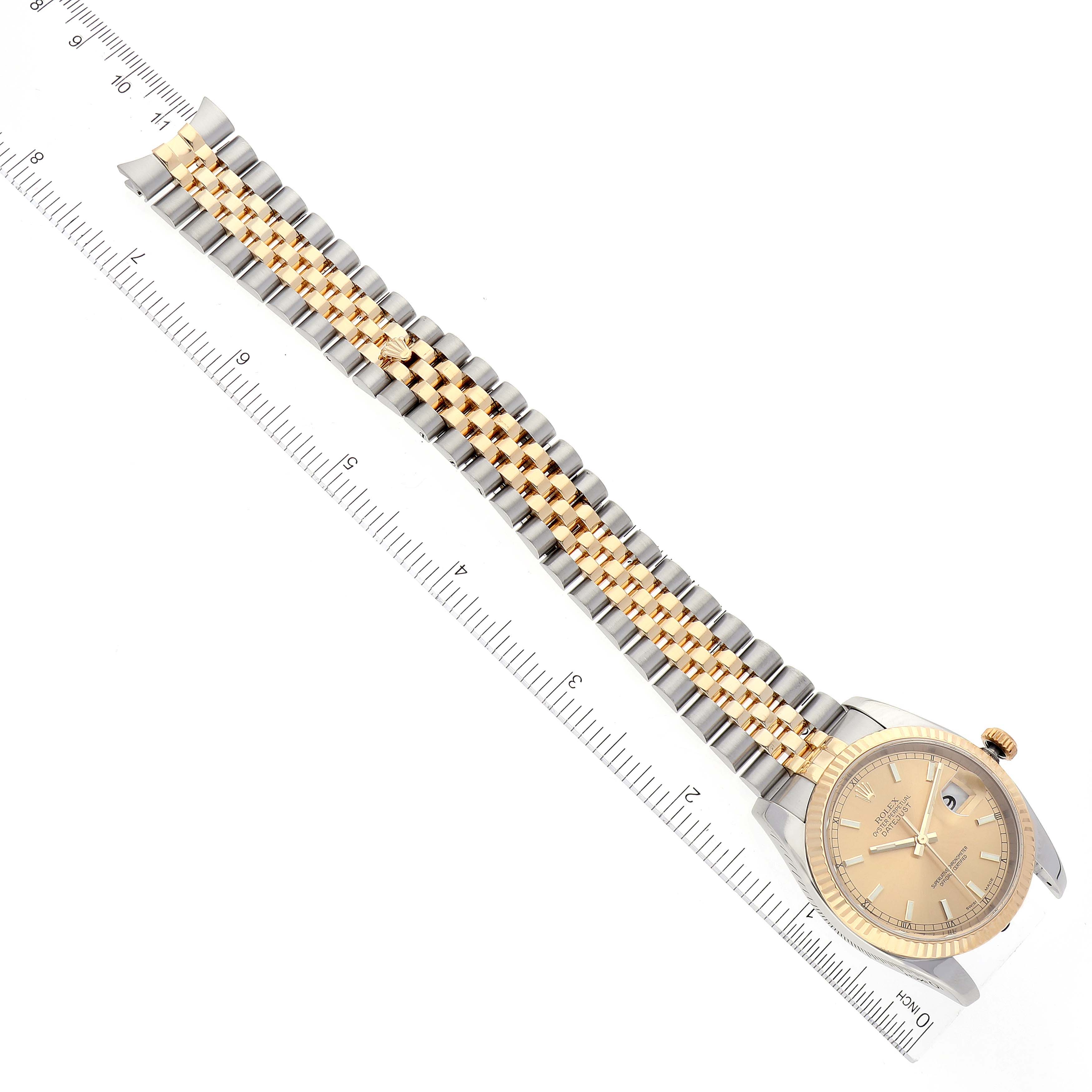 The image shows a Rolex Datejust 116233 Men's Steel and Gold (two tone) Champagne Dial 116233 Men's Steel and Gold (two tone) Champagne Dial watch positioned diagonally, highlighting its face, bezel, and two-tone jubilee bracelet next to a ruler.