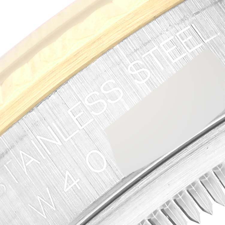 This close-up image shows part of the bezel and case of a Rolex Datejust 16233 Men's Steel and Gold (two tone) Champagne Dial 16233 Men's Steel and Gold (two tone) Champagne Dial watch, with "STAINLESS STEEL" and "W 40" engraved.