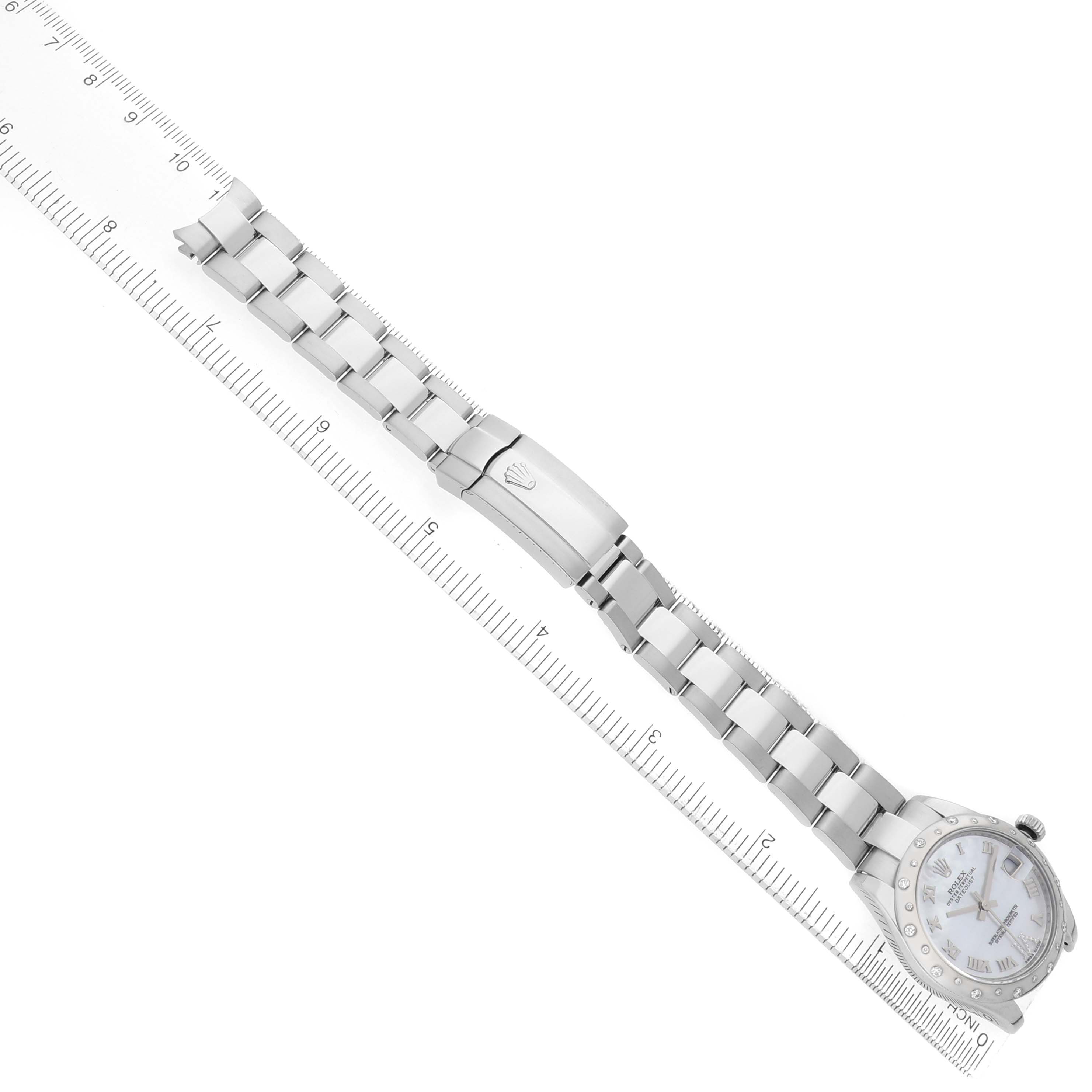The Rolex Mid-Size 178344 Women's Stainless Steel Mother of Pearl Dial watch is shown from an angled top view, displaying its bracelet and clasp alongside a ruler.