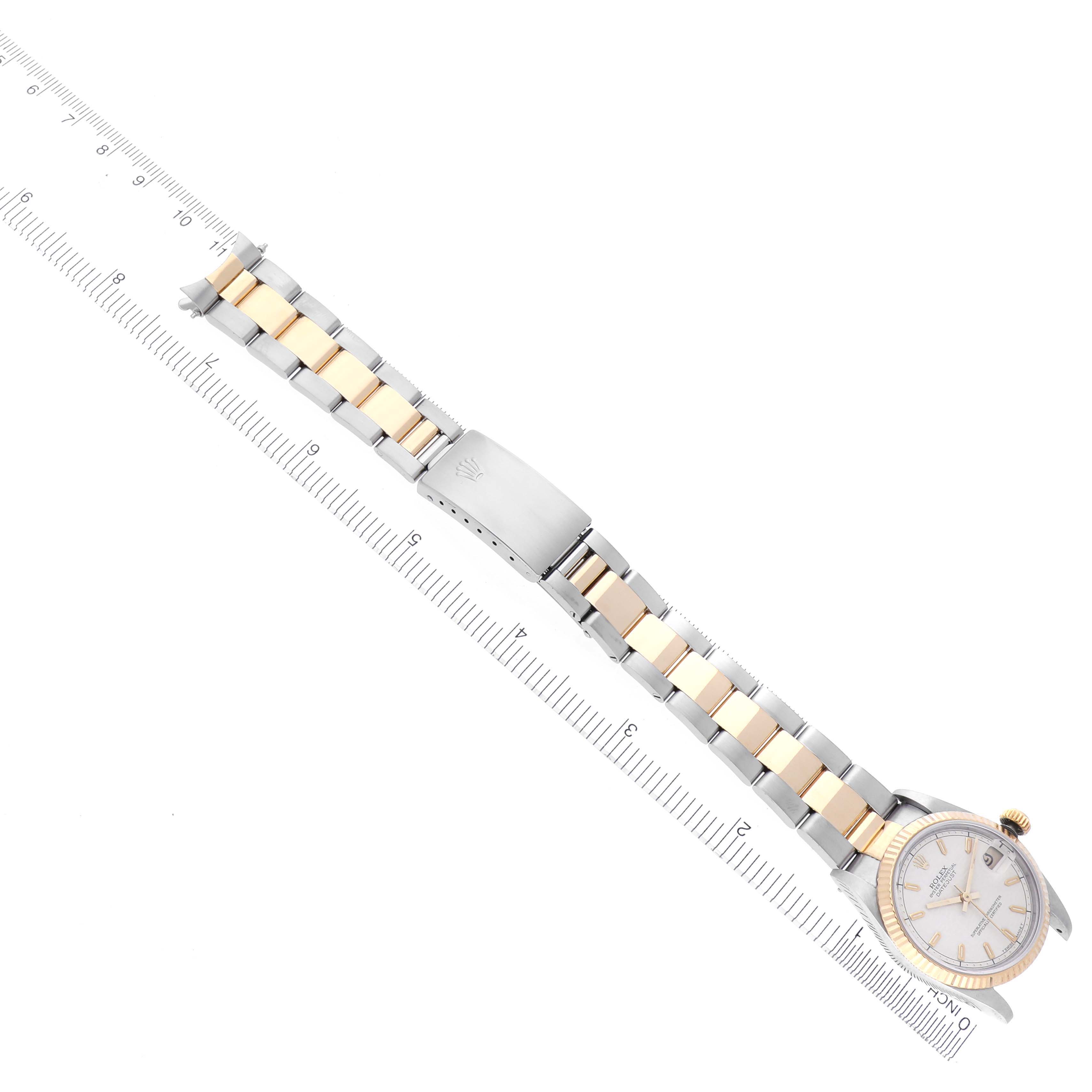 The Rolex Mid-Size 68273 Women's Steel and Gold (two tone) Silver Dial 68273 Women's Steel and Gold (two tone) Silver Dial watch is shown from a top-down angle, highlighting the face, bezel, and bracelet alongside a ruler.