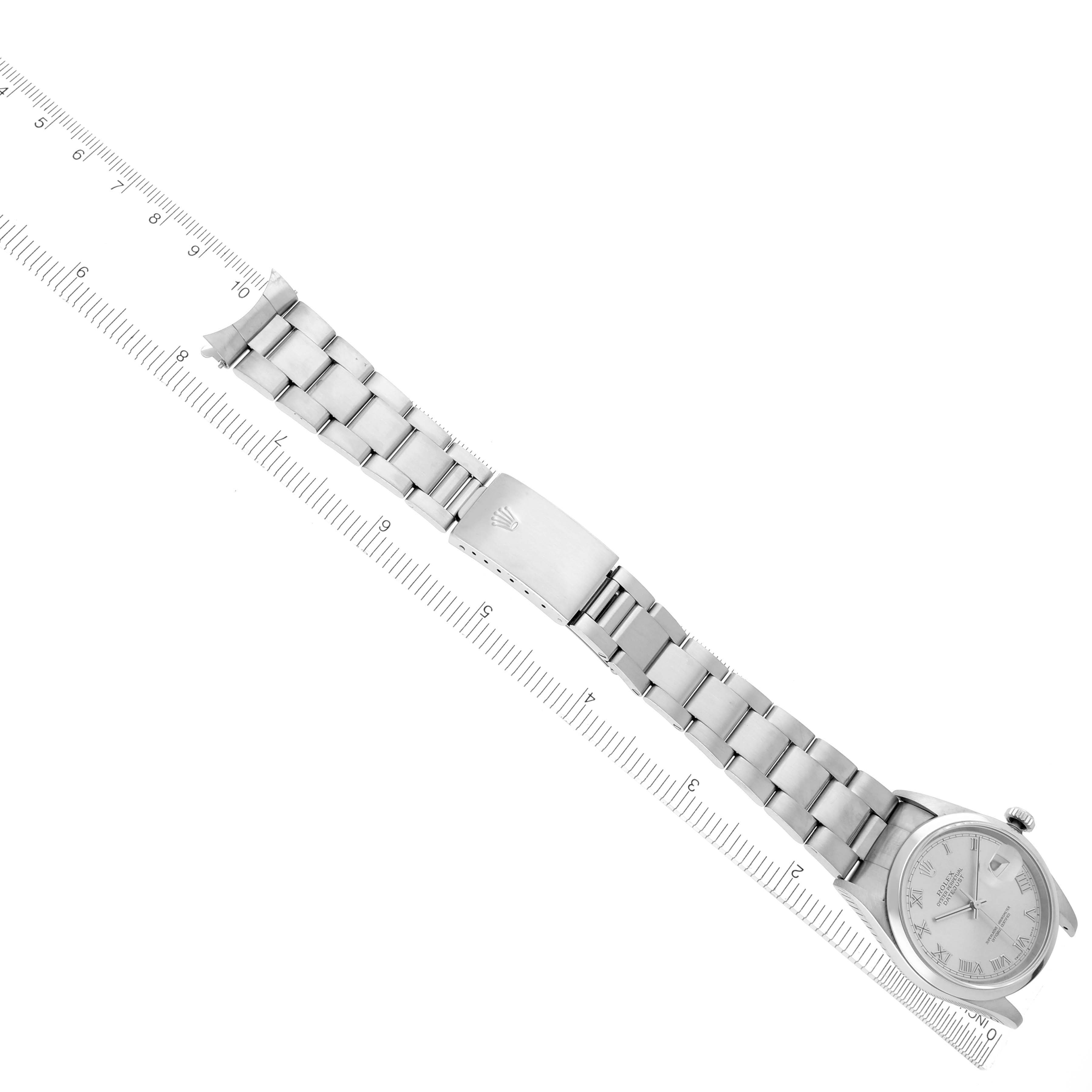 The Rolex Datejust 16200 Men's Stainless Steel Silver Dial watch is shown from an angled top view, featuring the dial, bracelet, and clasp beside a ruler.