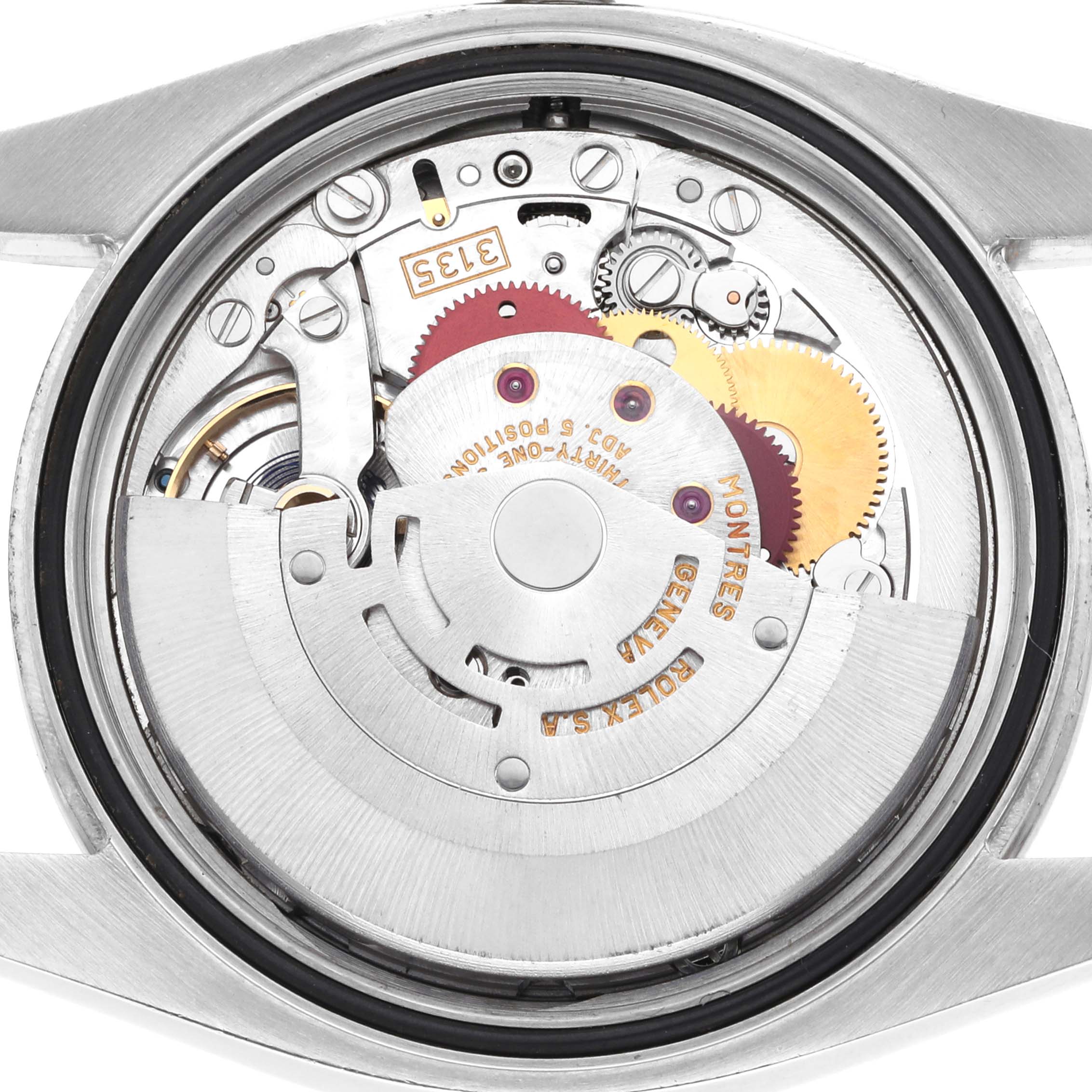 The image shows the movement of a Rolex Datejust 116244 Men's Stainless Steel Silver Dial watch from a back angle, displaying gears and mechanical components.