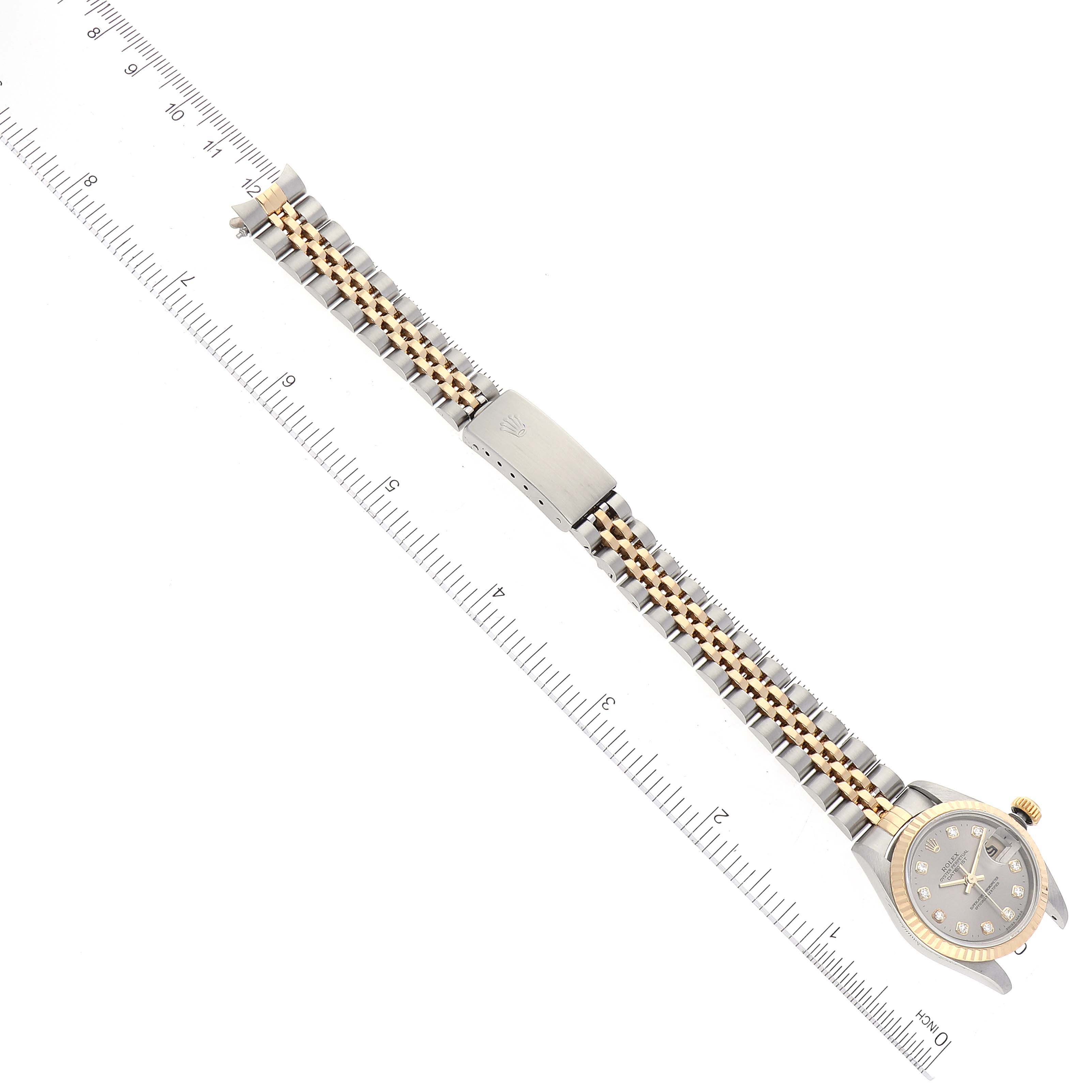 The image shows a top view of a Rolex Datejust 69173 Women's Steel and Gold (two tone) Grey Dial 69173 Women's Steel and Gold (two tone) Grey Dial watch with its full bracelet and clasp alongside a ruler for scale.