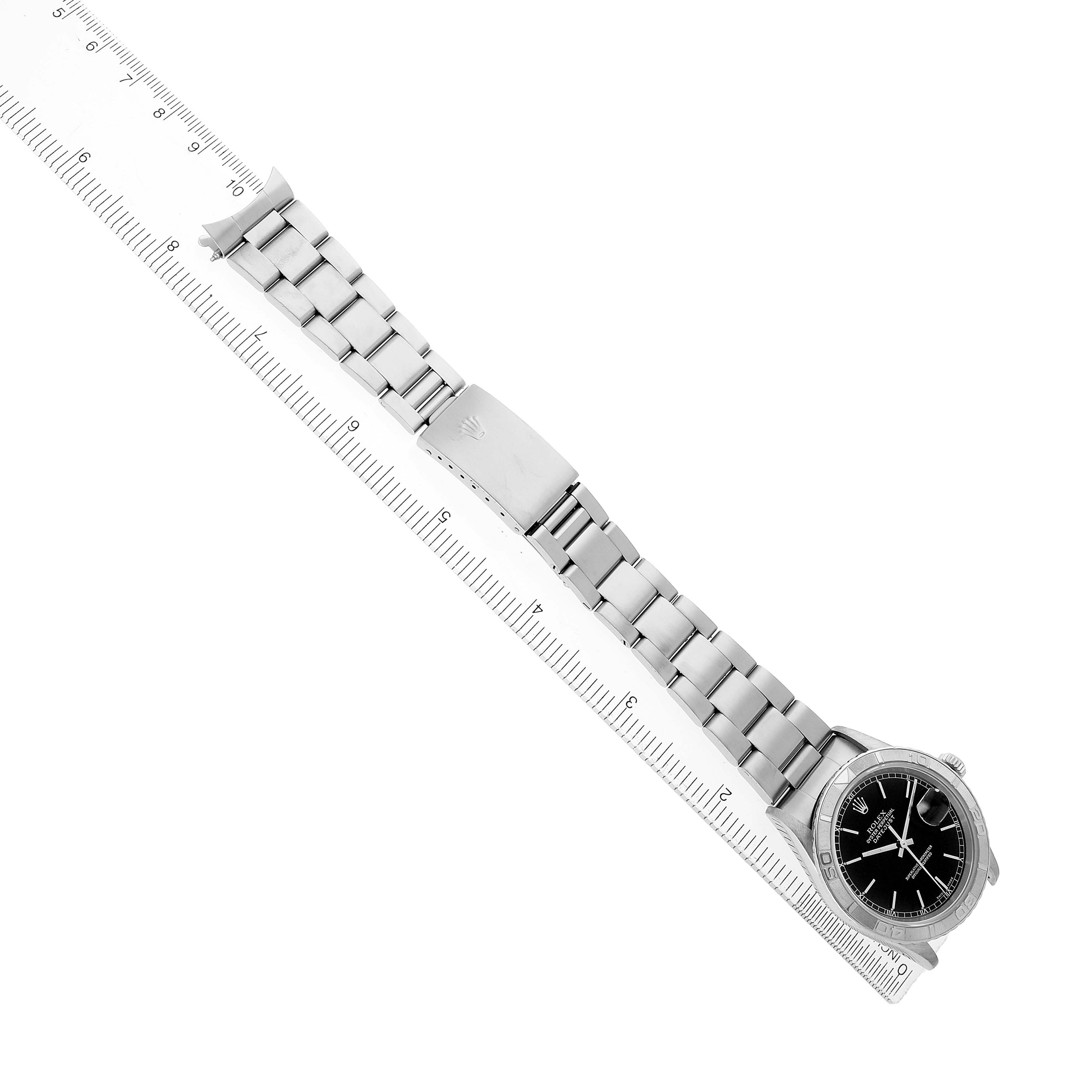 The Rolex Turn-o-Graph 16264 Men's Stainless Steel Black Dial watch is shown at an angle displaying the full bracelet and clasp alongside a clear ruler.