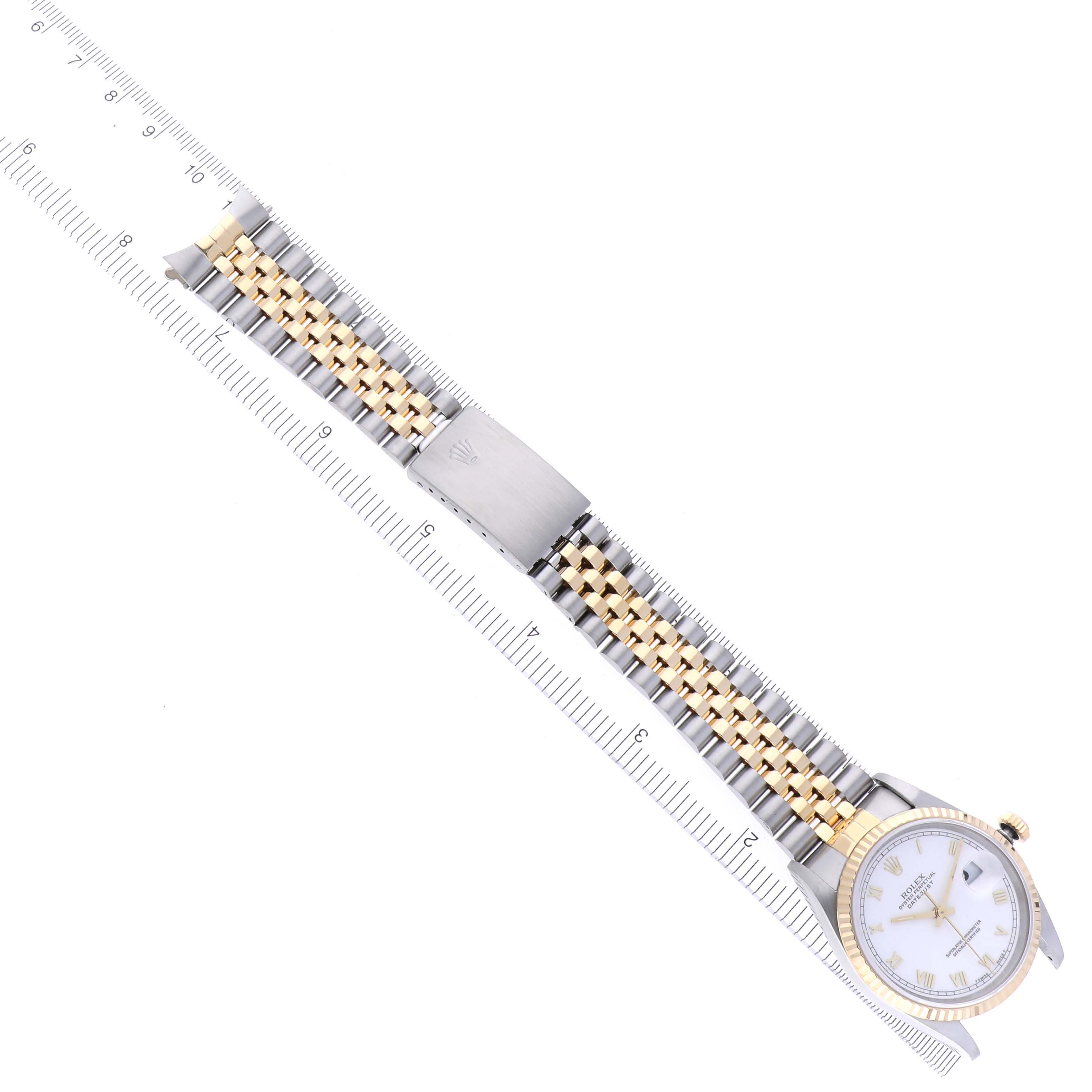 The Rolex Datejust 16233 Men
s Steel and Gold (two tone) White Dial 16233 Men
s Steel and Gold (two tone) White Dial watch is displayed flat, showing the face, two-tone bracelet, and clasp alongside a ruler for scale.